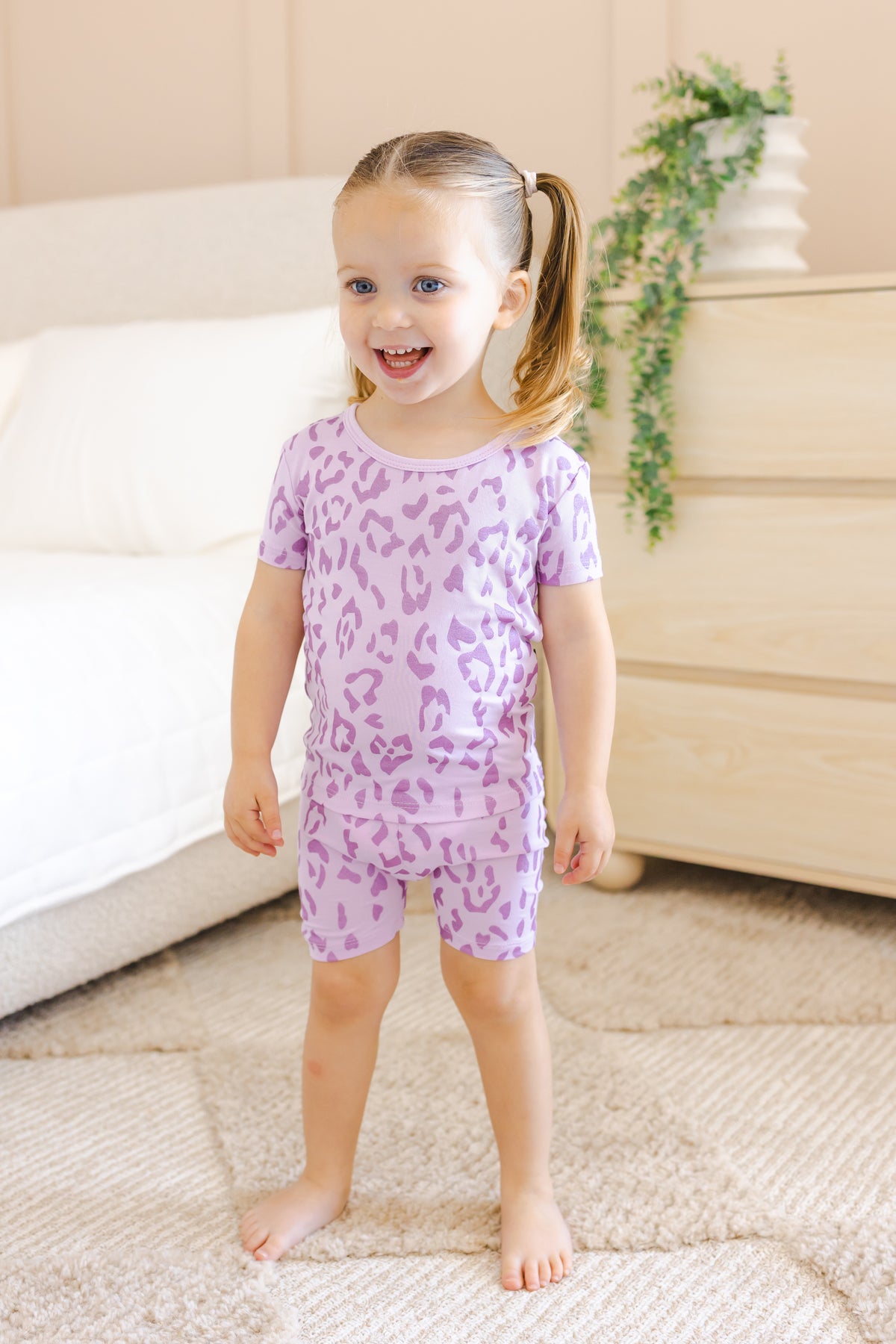 Child wearing Short Sleeve Pajamas in Thistle Leopard print in a room