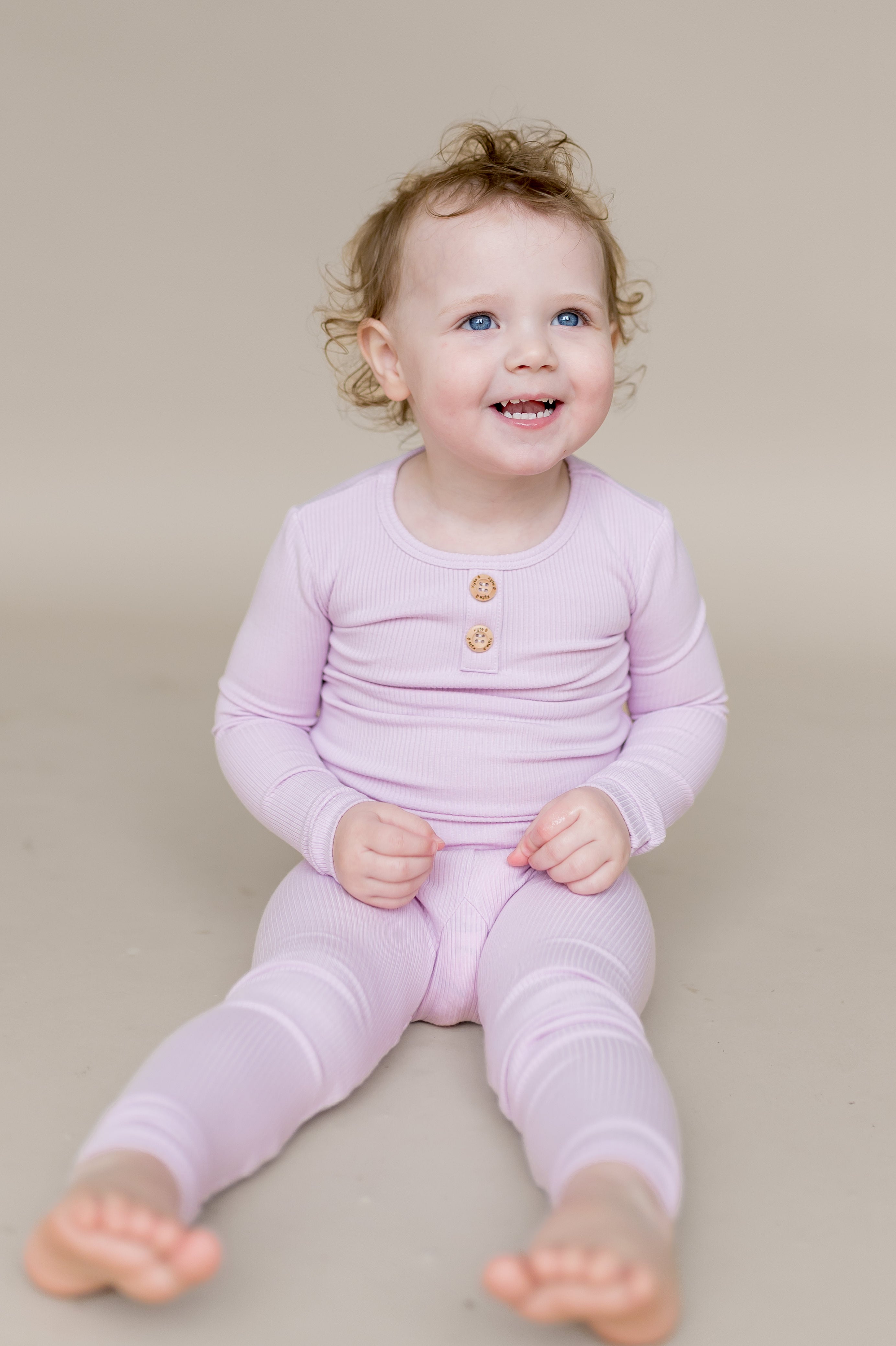 Young girl sitting on the floor wearing the Ribbed Henley Set in Thistle