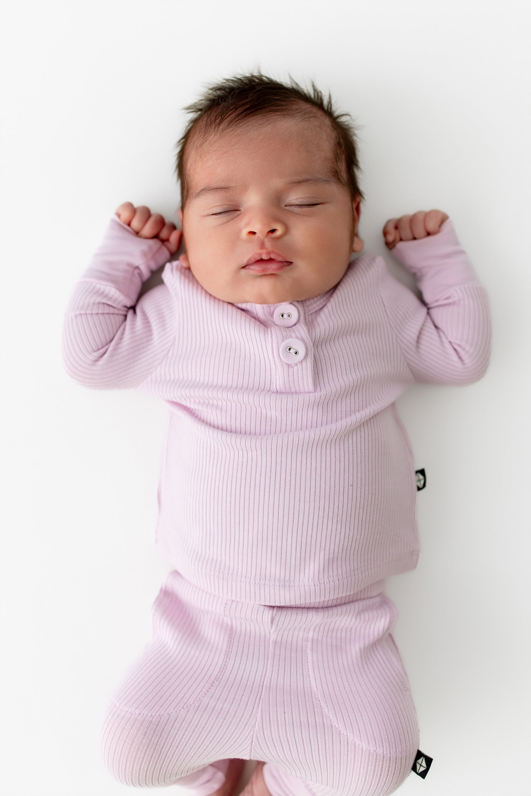 Close up of sleeping newborn wearing the Ribbed Infant Henley Set in Thistle