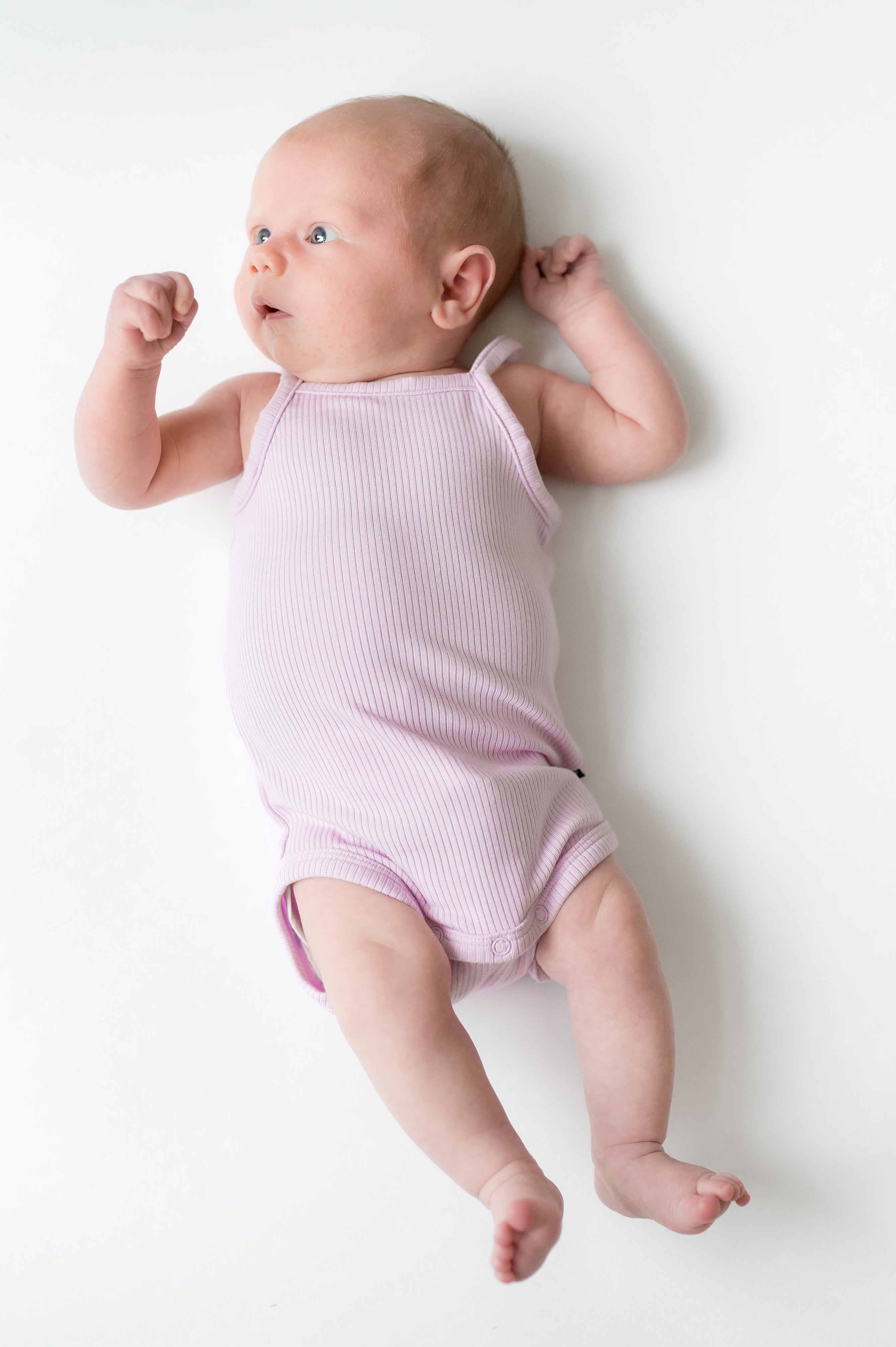 Newborn stretching wearing the Ribbed Spaghetti Strap Bodysuit in Thistle