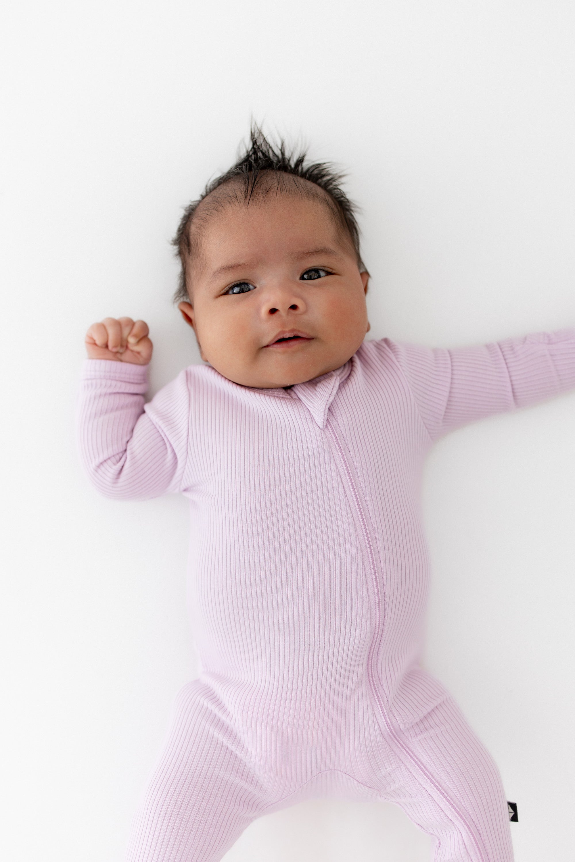 Close up of a newborn wearing the Ribbed Zipper Footie in Thistle