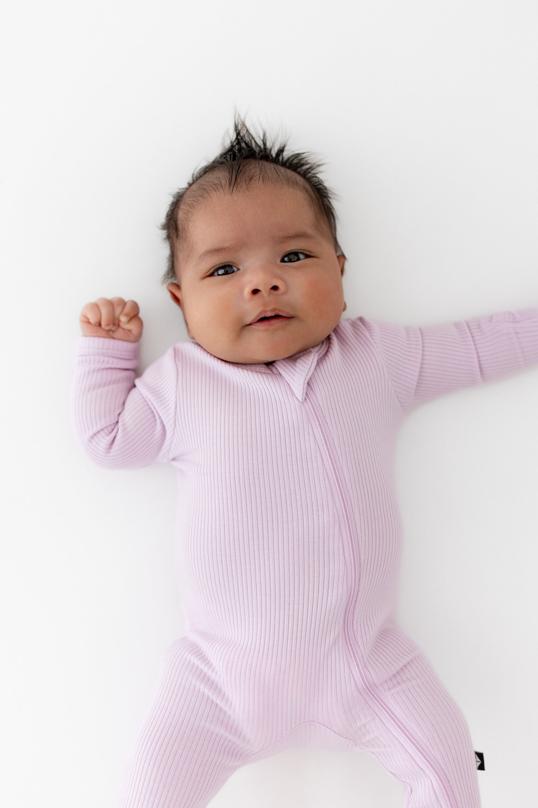 Close up of a newborn wearing the Ribbed Zipper Footie in Thistle