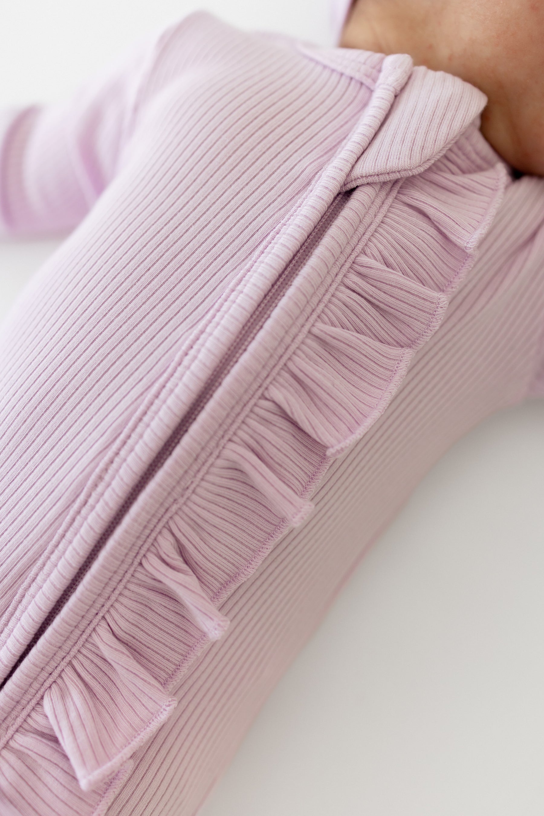 Close up of the ribbed ruffle fabric along the zipper of the Ribbed Ruffle Zipper Footie in Thistle