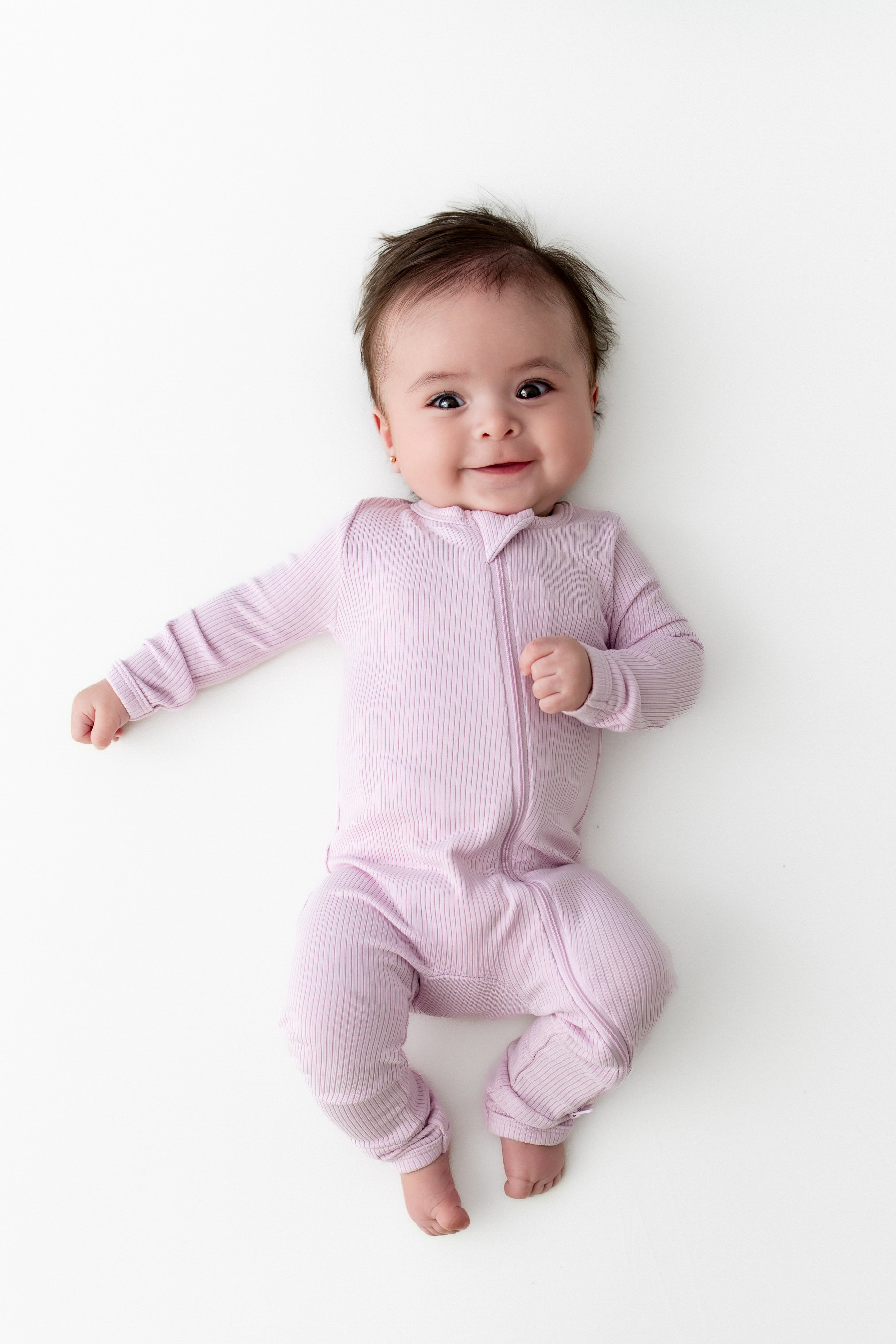 Young smiling infant wearing the Ribbed Zipper Romper in Thistle