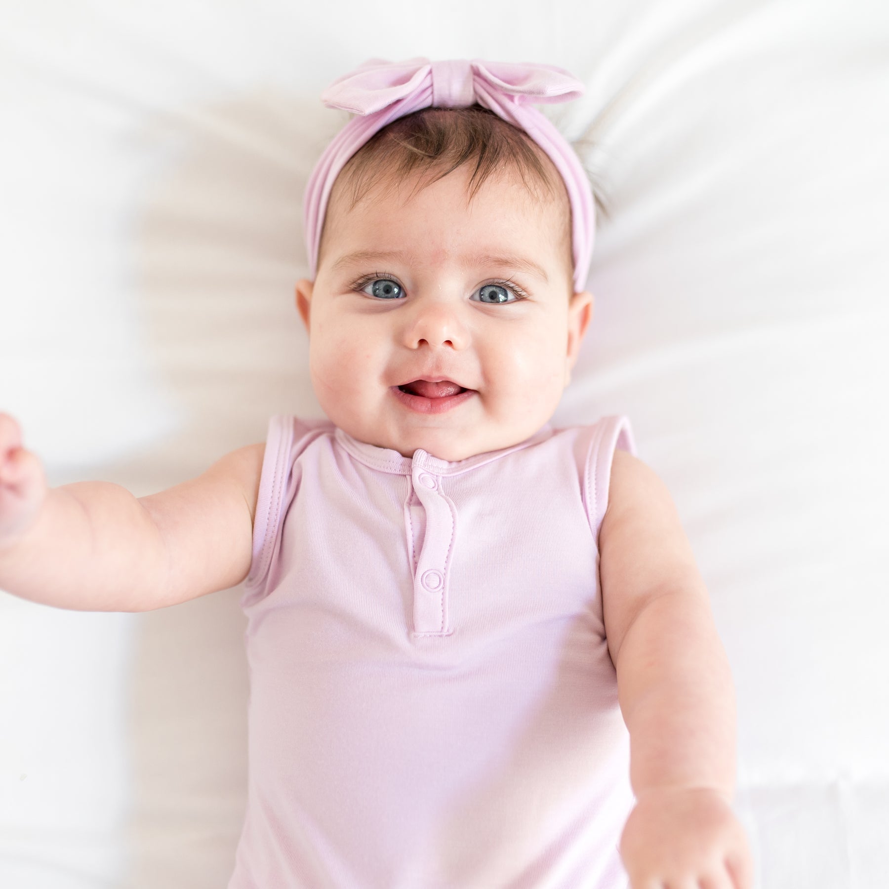 Baby wearing a purple outfit and headband on a white background