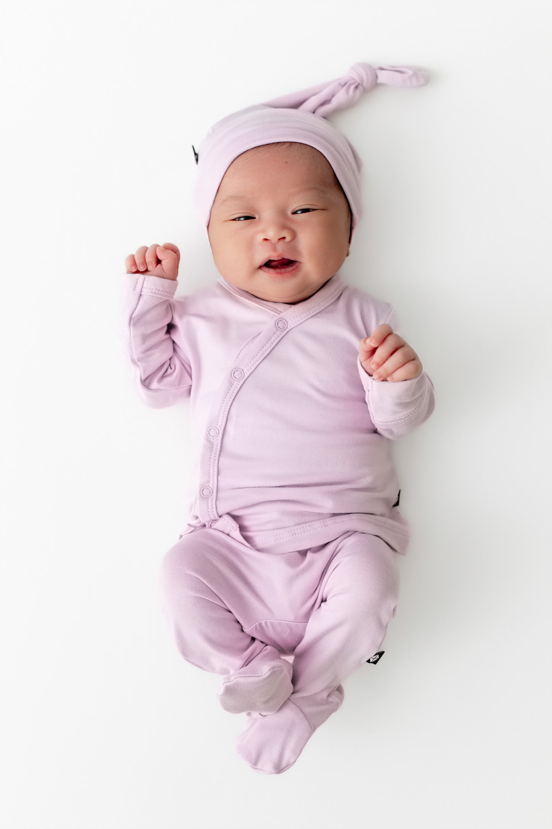Baby wearing a light purple outfit and hat on a white background