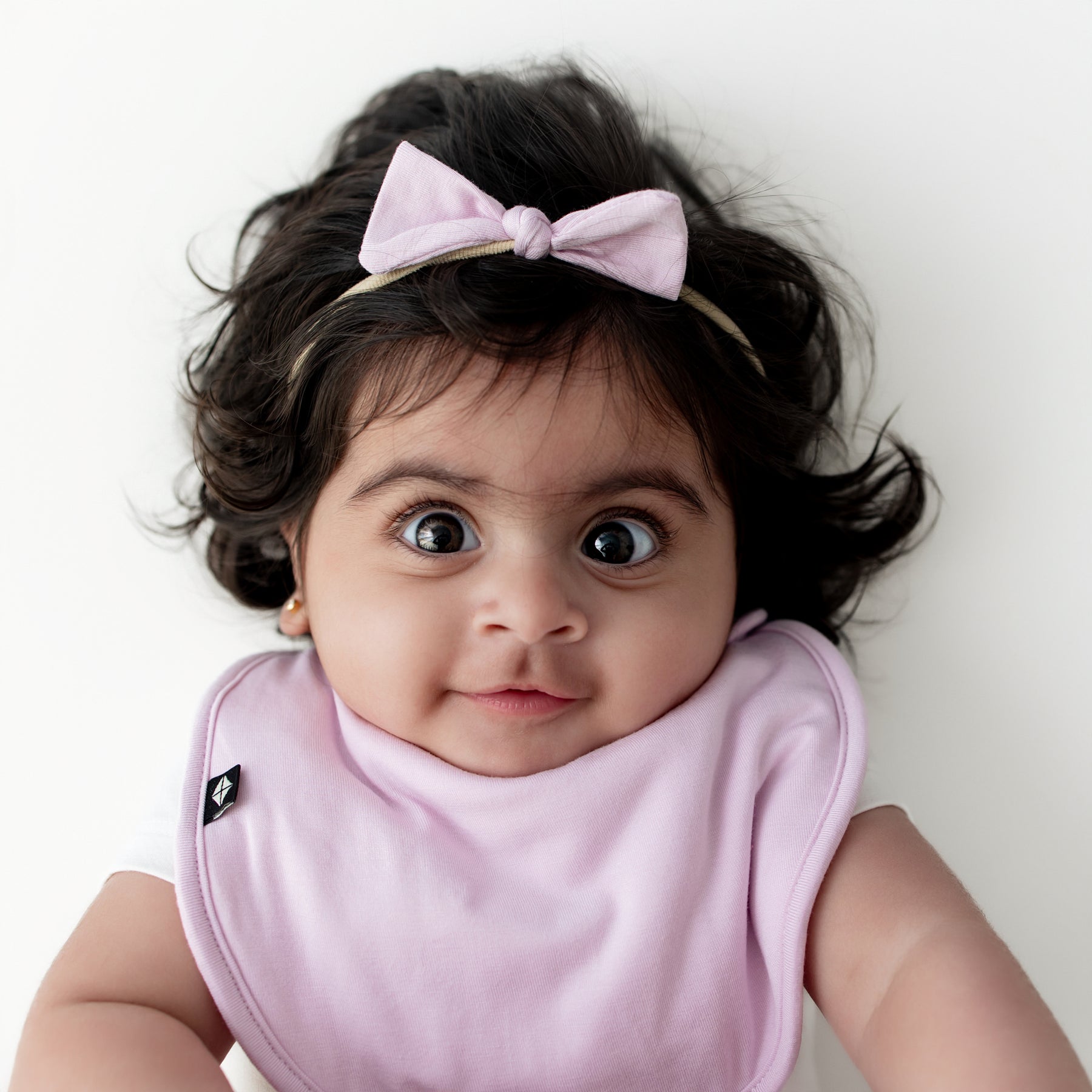 Young infant wearing the Tiny Nylon Bow in Thistle with matching cushy bib