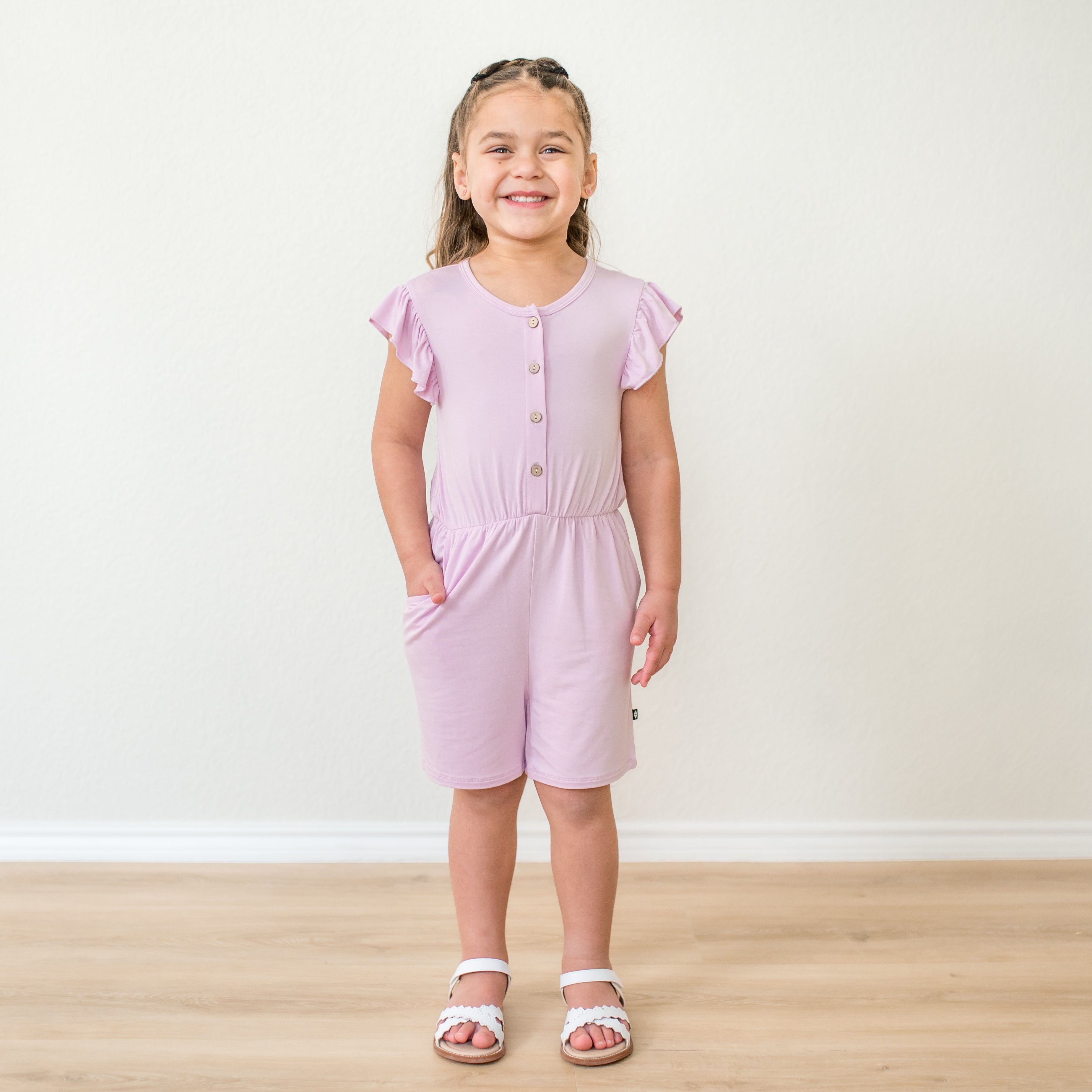 Young girl wearing a flutter sleeve romper in a light purple color