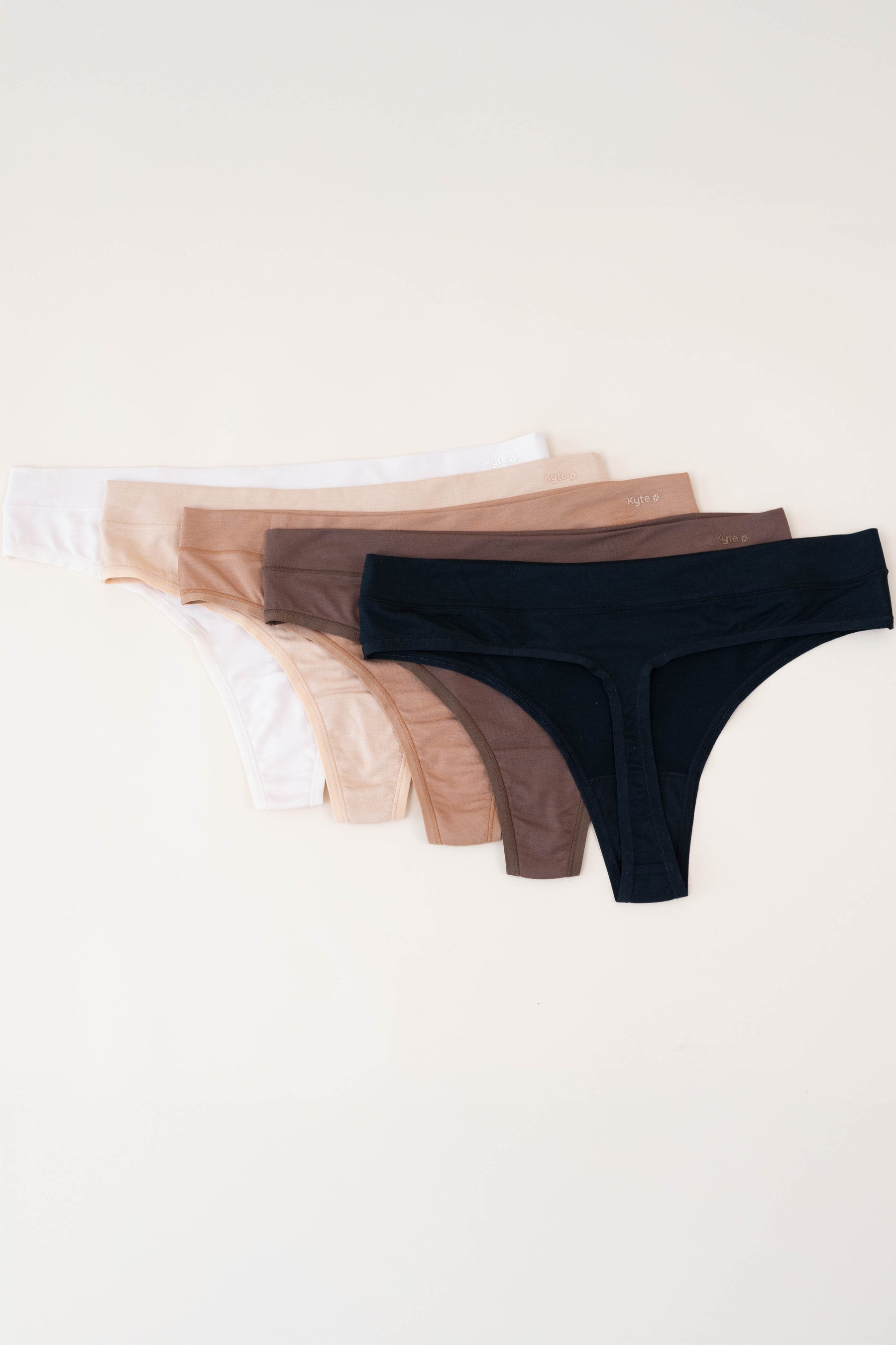 Flat lay of all women's thongs laying on a light neutral surface