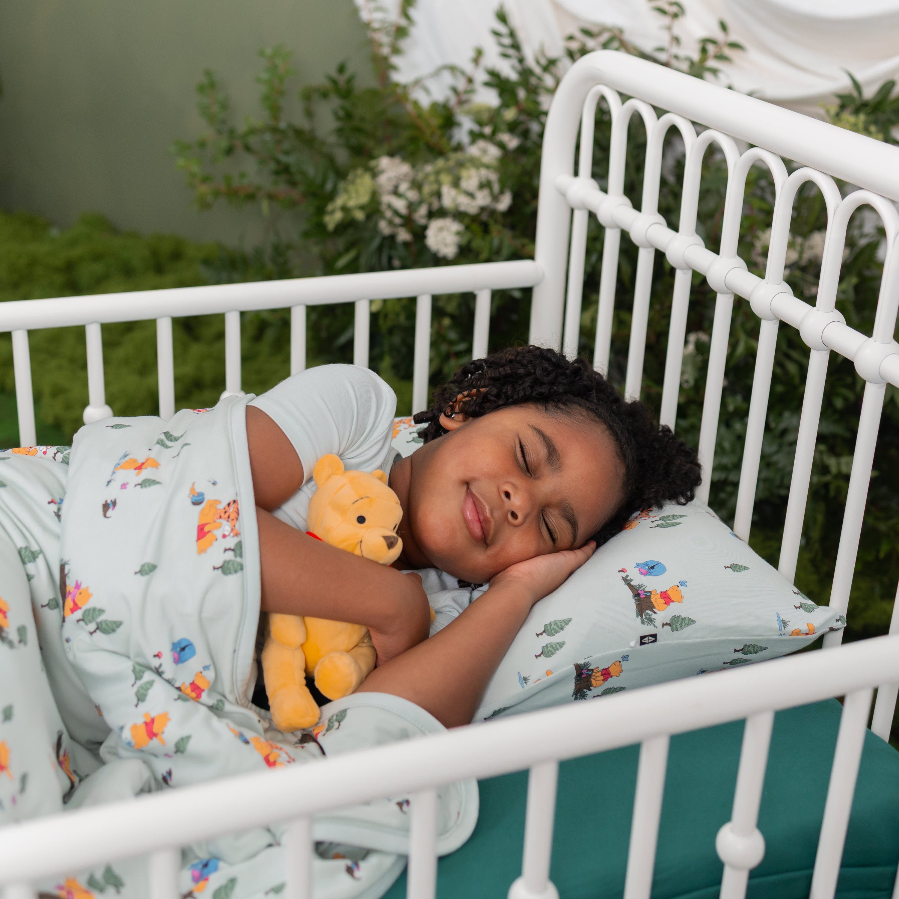 Young girl laying in bed on a Toddler Pillowcase in Winnie the Pooh Hundred Acre Wood with a matching blanket on top of her