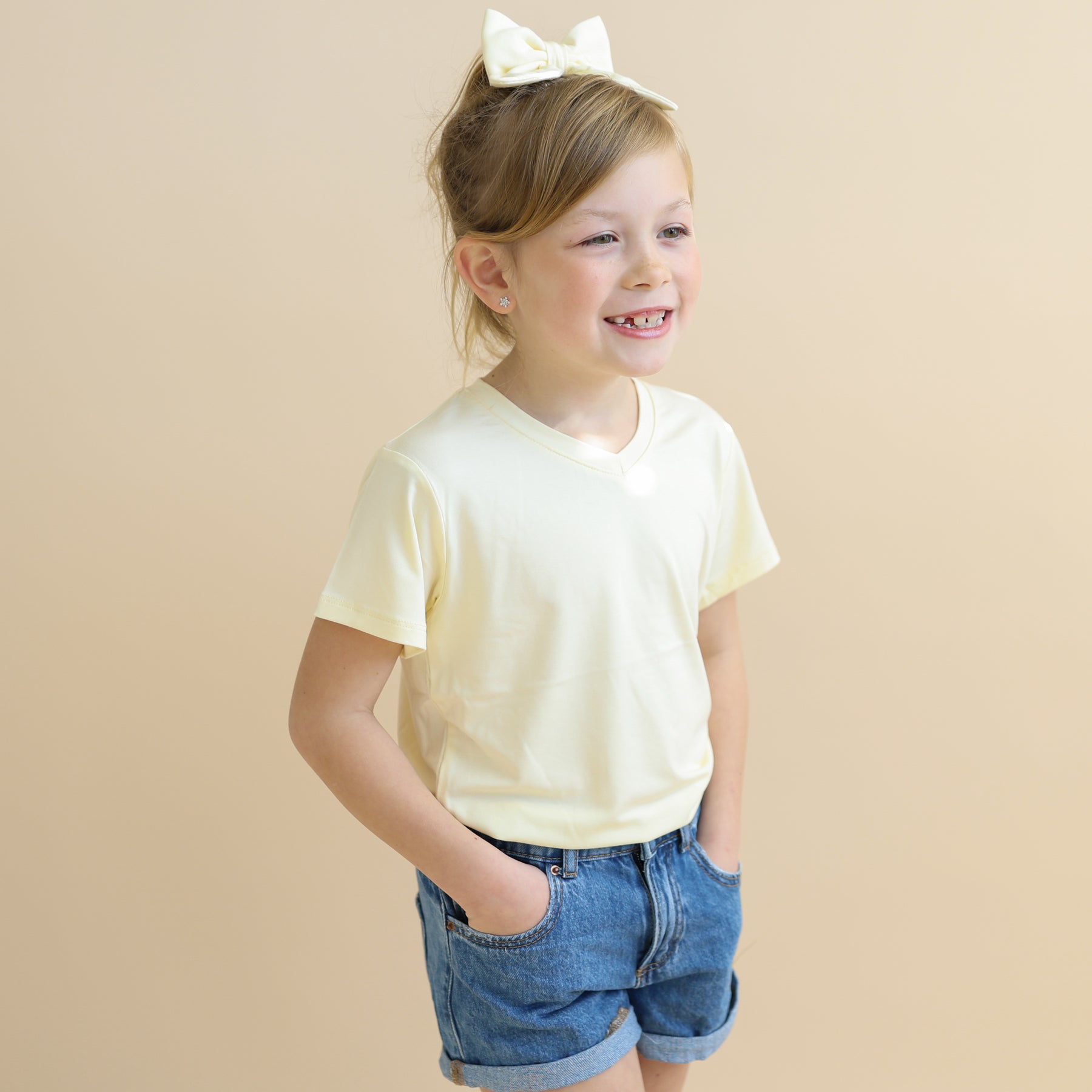 Close up of young girl wearing the Toddler V-Neck Tee in Chamomile with her hands in the shorts pocket