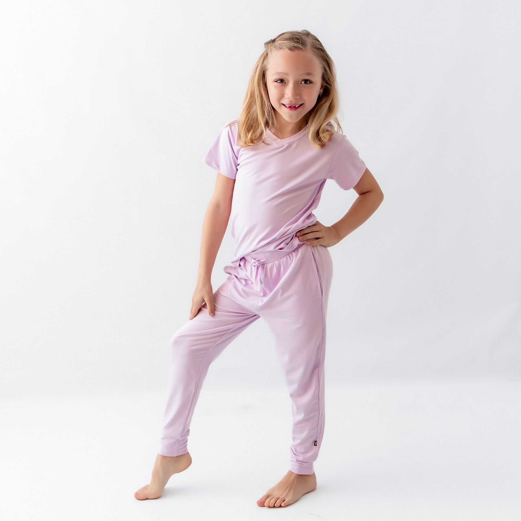 Young girl standing in front of a white background wearing the Toddler Jogger Pant in Thistle paired with matching toddler V-Neck