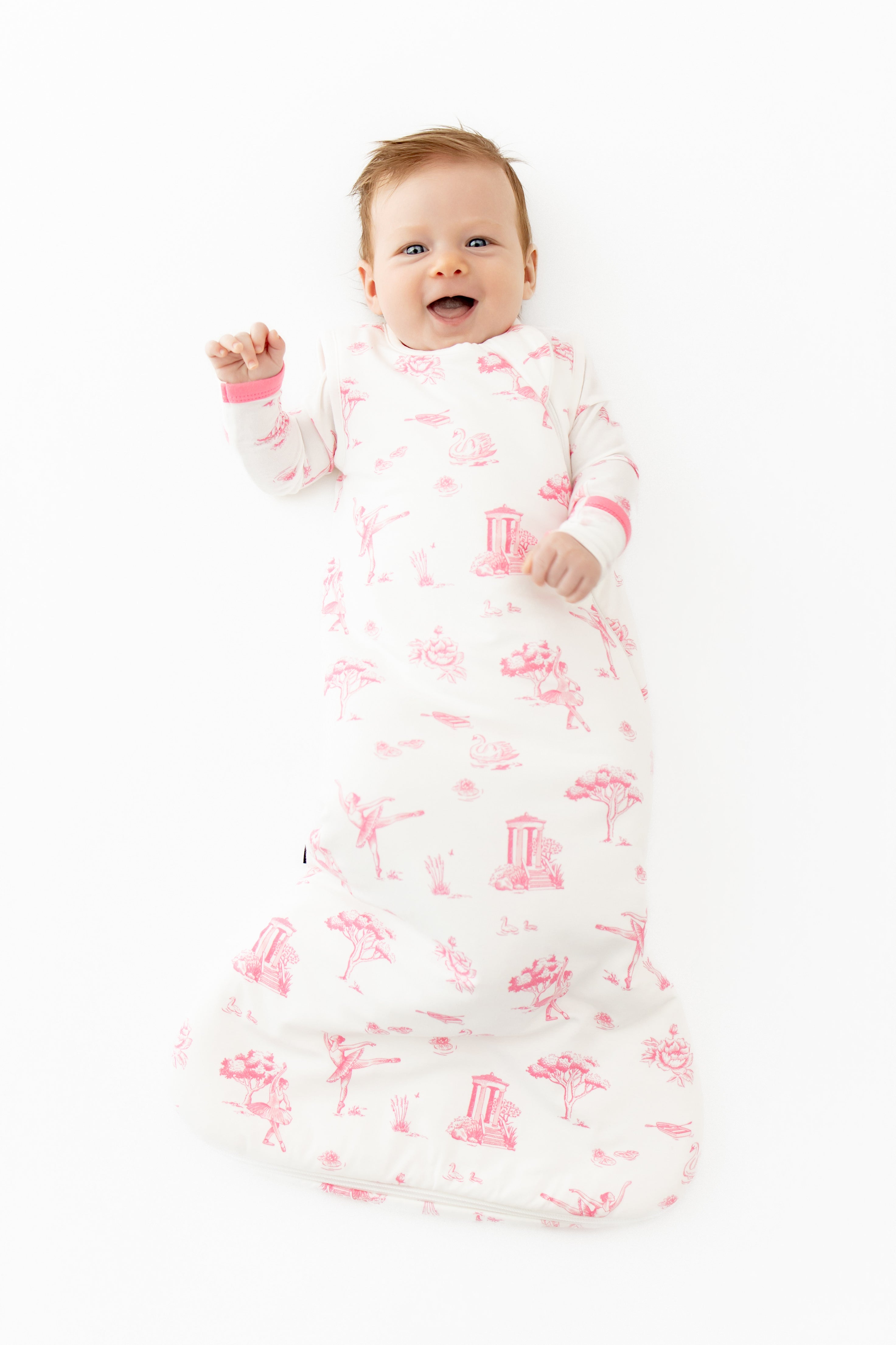 Smiling toddler wearing the Sleep Bag in Toile Ballet 1.0 with a matching romper on underneath