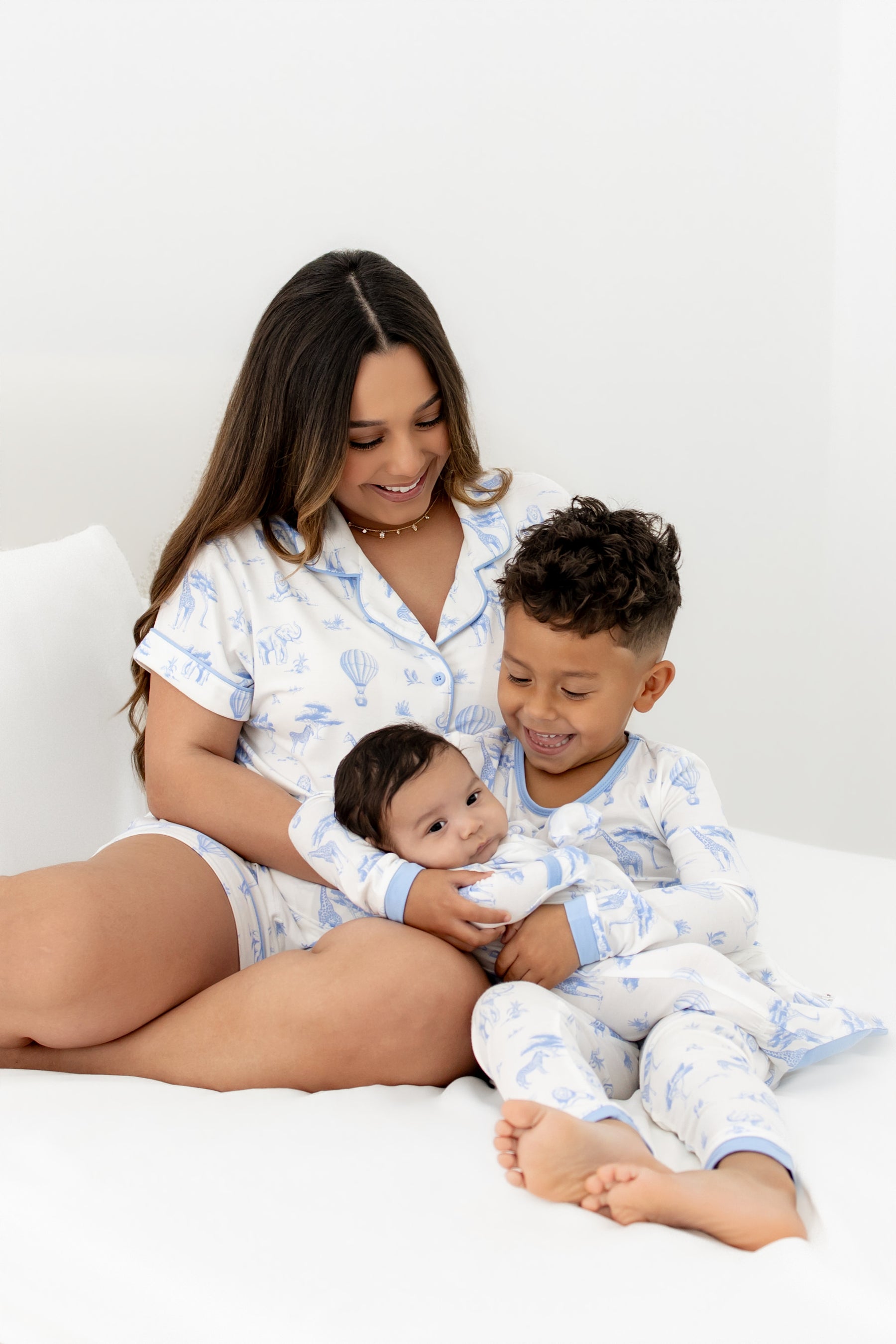 Woman and two children in matching pajamas sitting on a bed.
