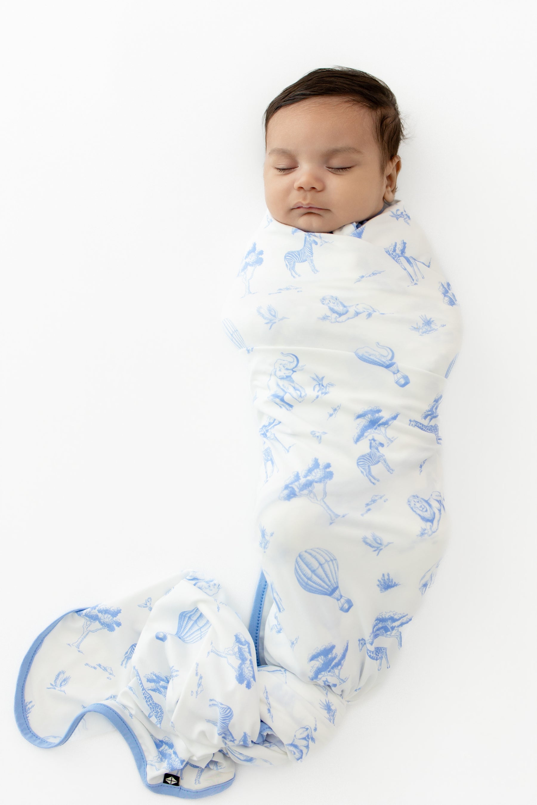Sleeping newborn swaddled in the Swaddle Blanket in Toile Safari