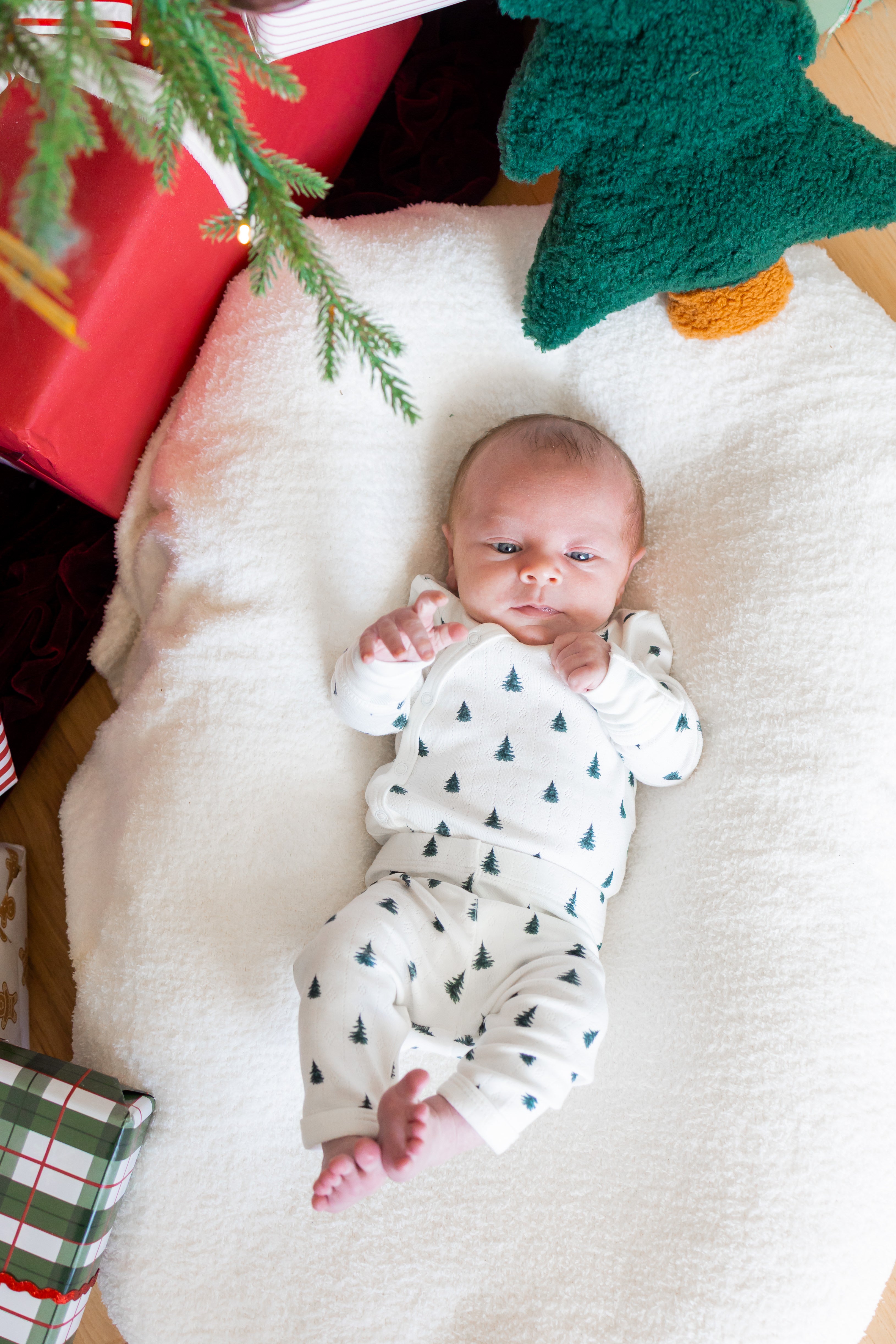 Baby wearing Pointelle Kimono Set in Christmas Trees lying on white sheet near a Christmas tree