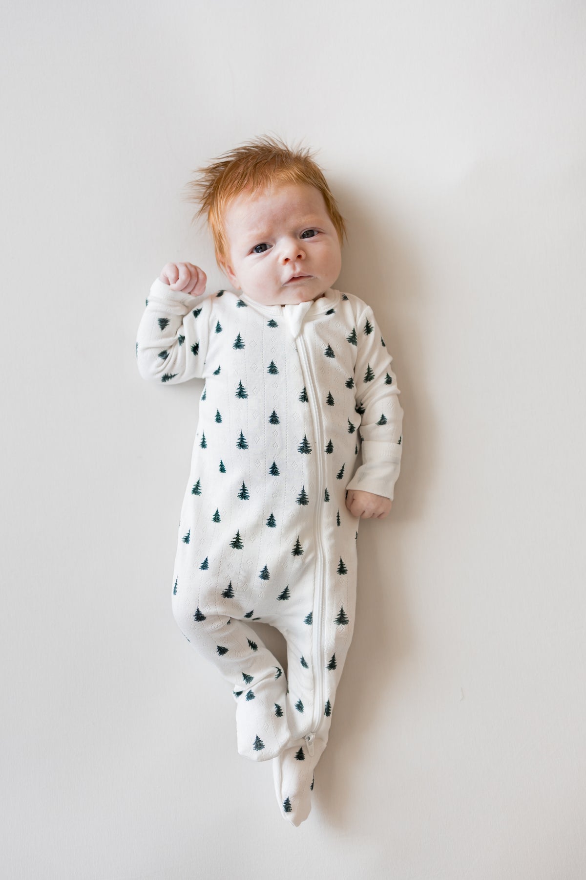 Baby wearing Pointelle Zippered Footie in Christmas Trees on a beige background