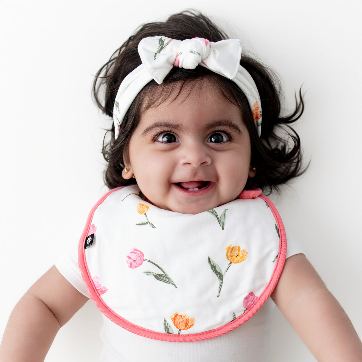 Close up of infant wearing the Cushy Bib in Tulip