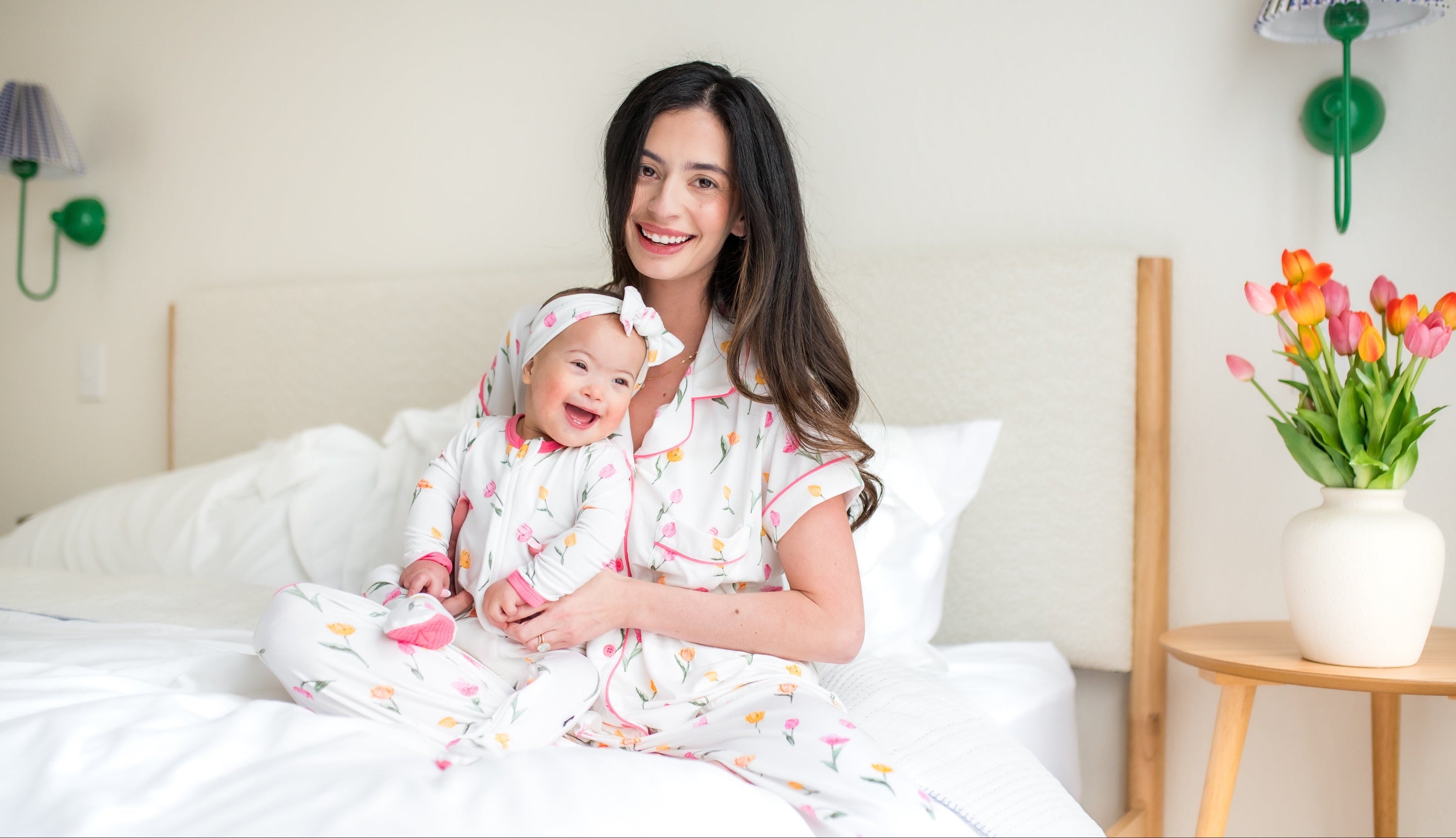 mom and baby in matching tulip printed pajamas sitting in a bedroom