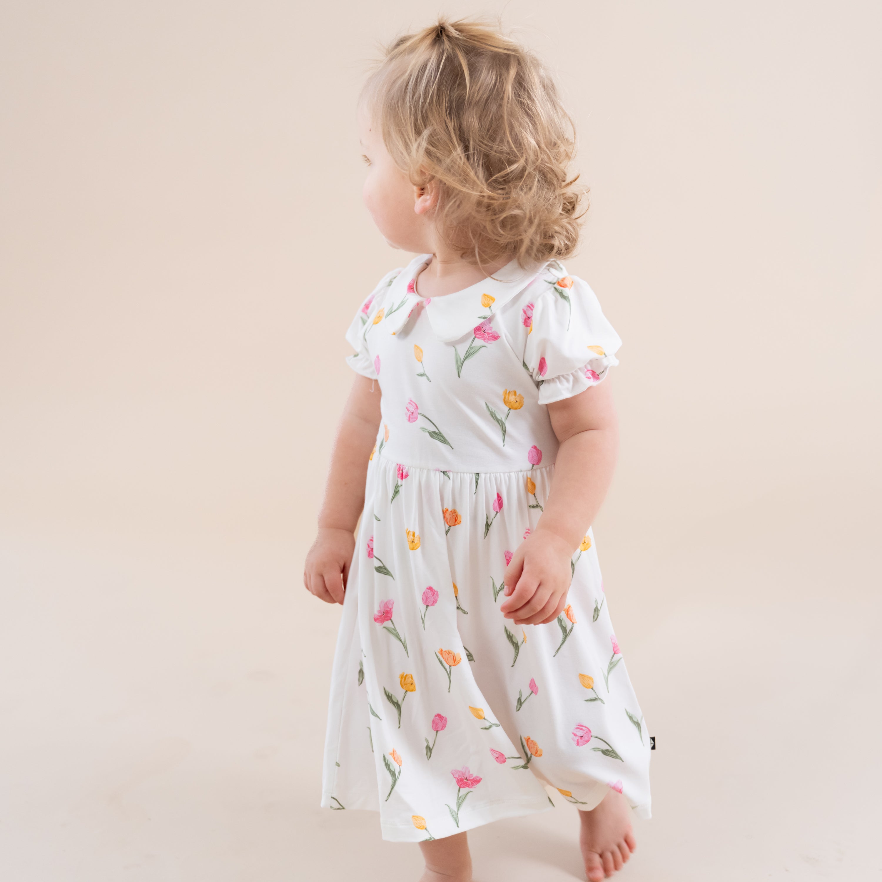 Young toddler walking wearing the Peter Pan Collar Bodysuit Dress in Tulip