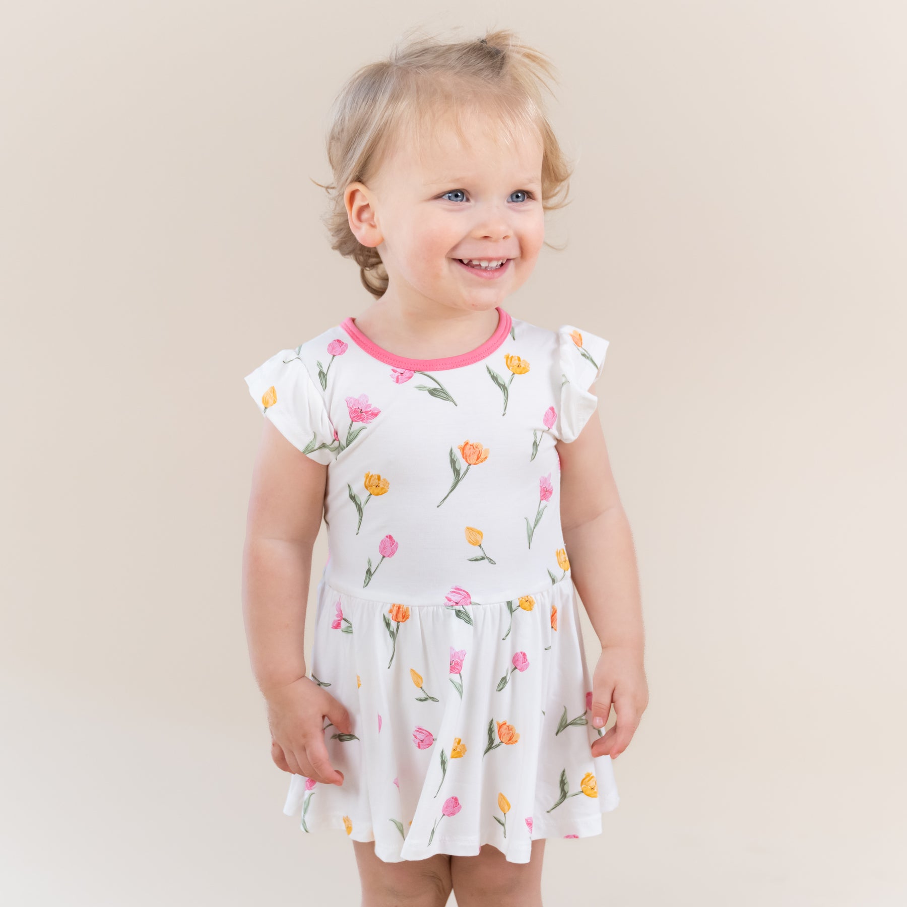 Young smiling toddler modeling the Twirl Bodysuit Dress in Tulip