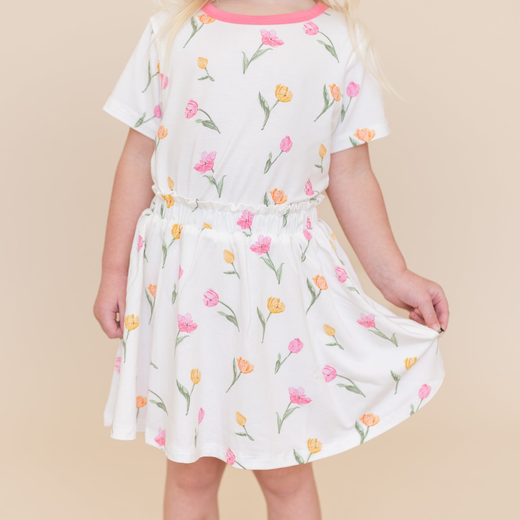 Young girl wearing the Toddler Skort in Tulip holding the hem of the skirt out paired with a matching basic tee