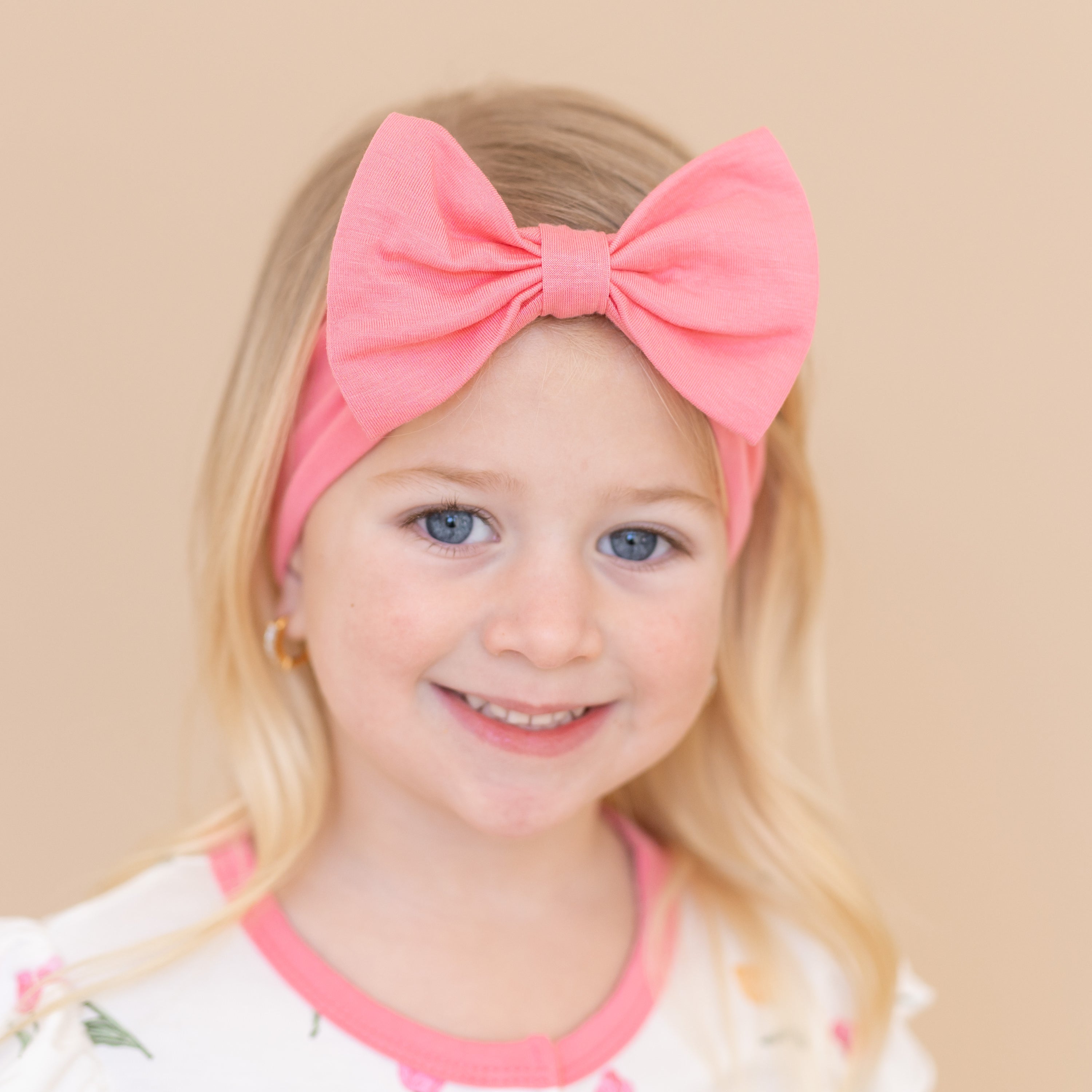 Close up of the Bow Headband in Guava shown on a young girl