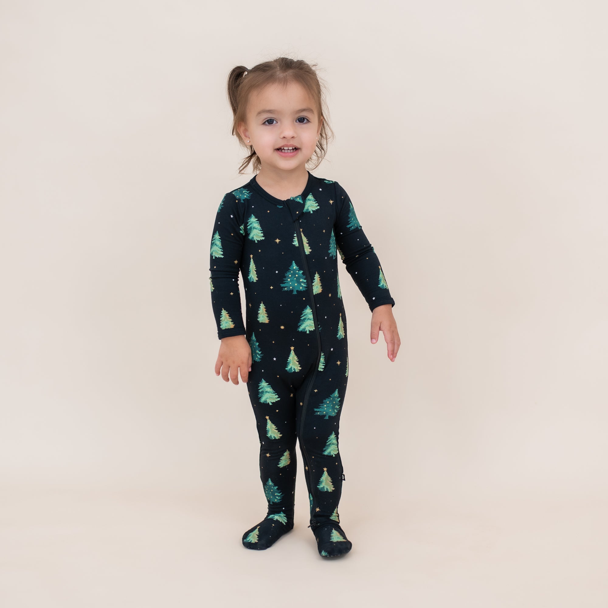 Toddler standing wearing the Zippered Footie in Twinkle Tree