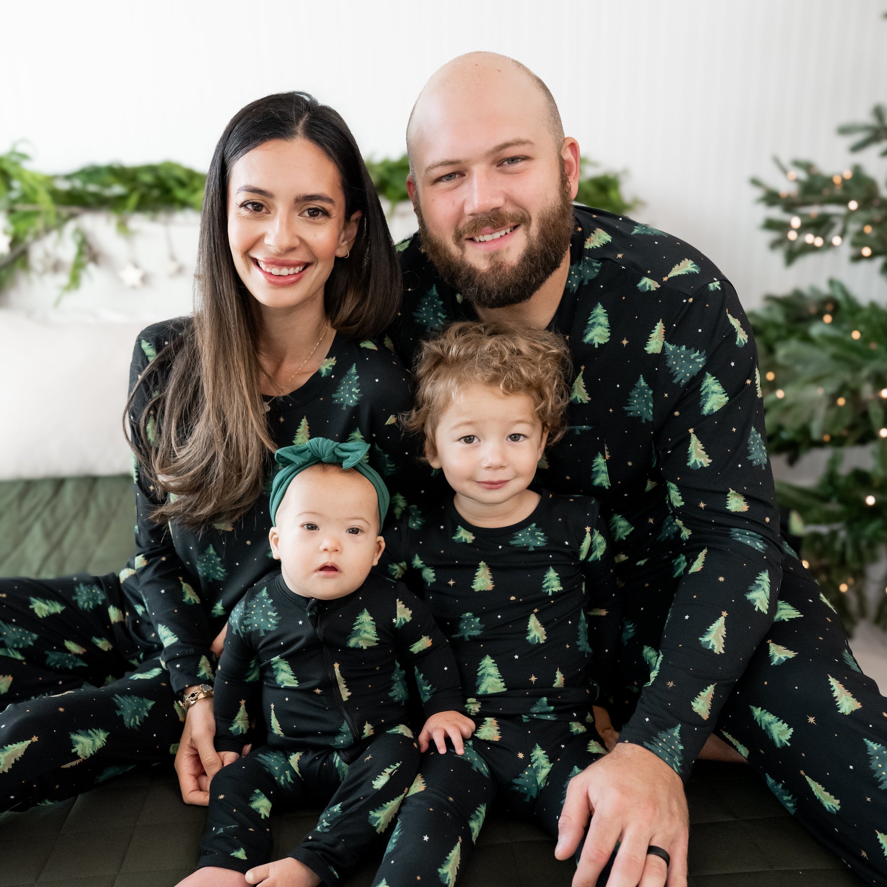 Family of four sitting on a bed matching in Twinkle Tree Pajamas