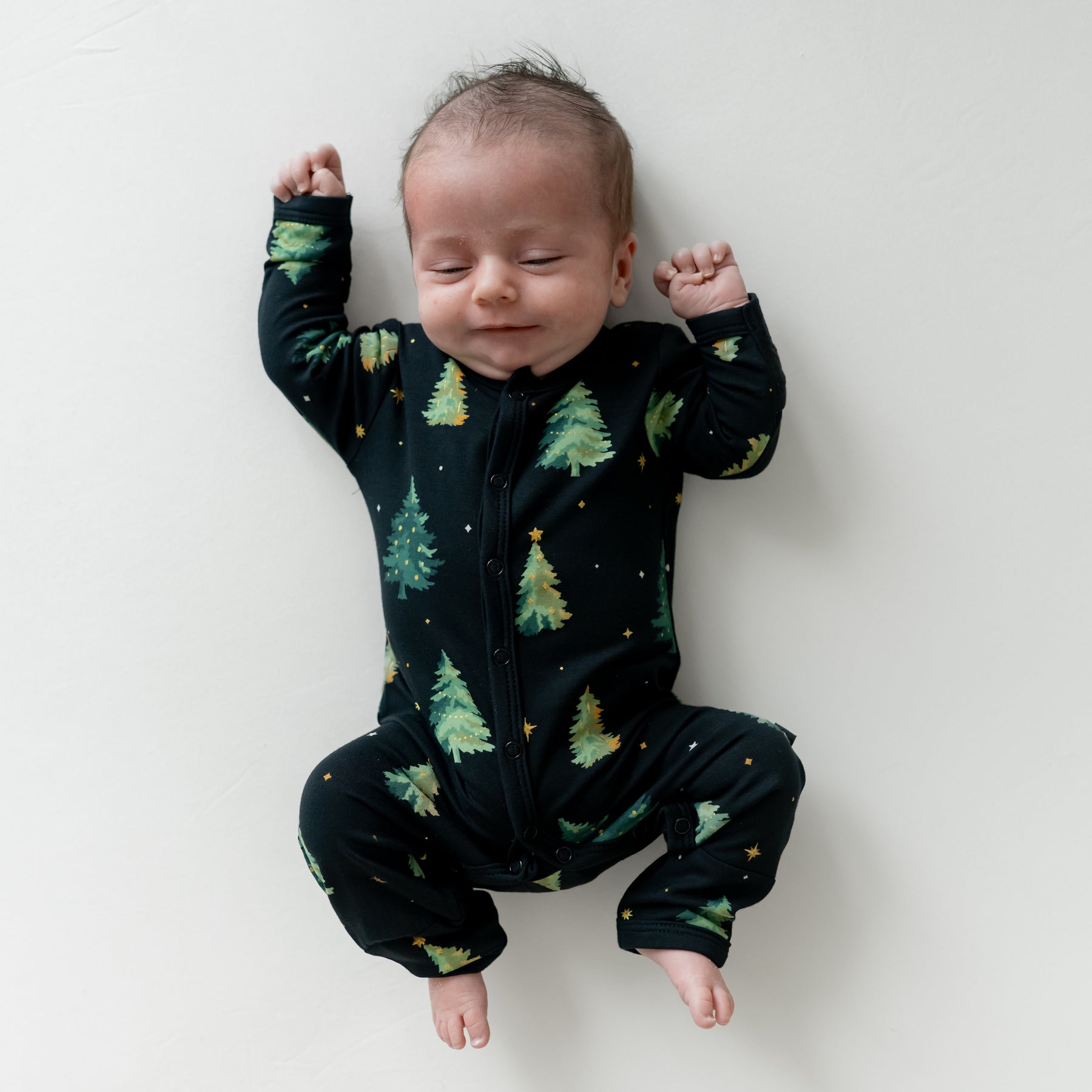 Infant laying down wearing the Romper in Twinkle Tree
