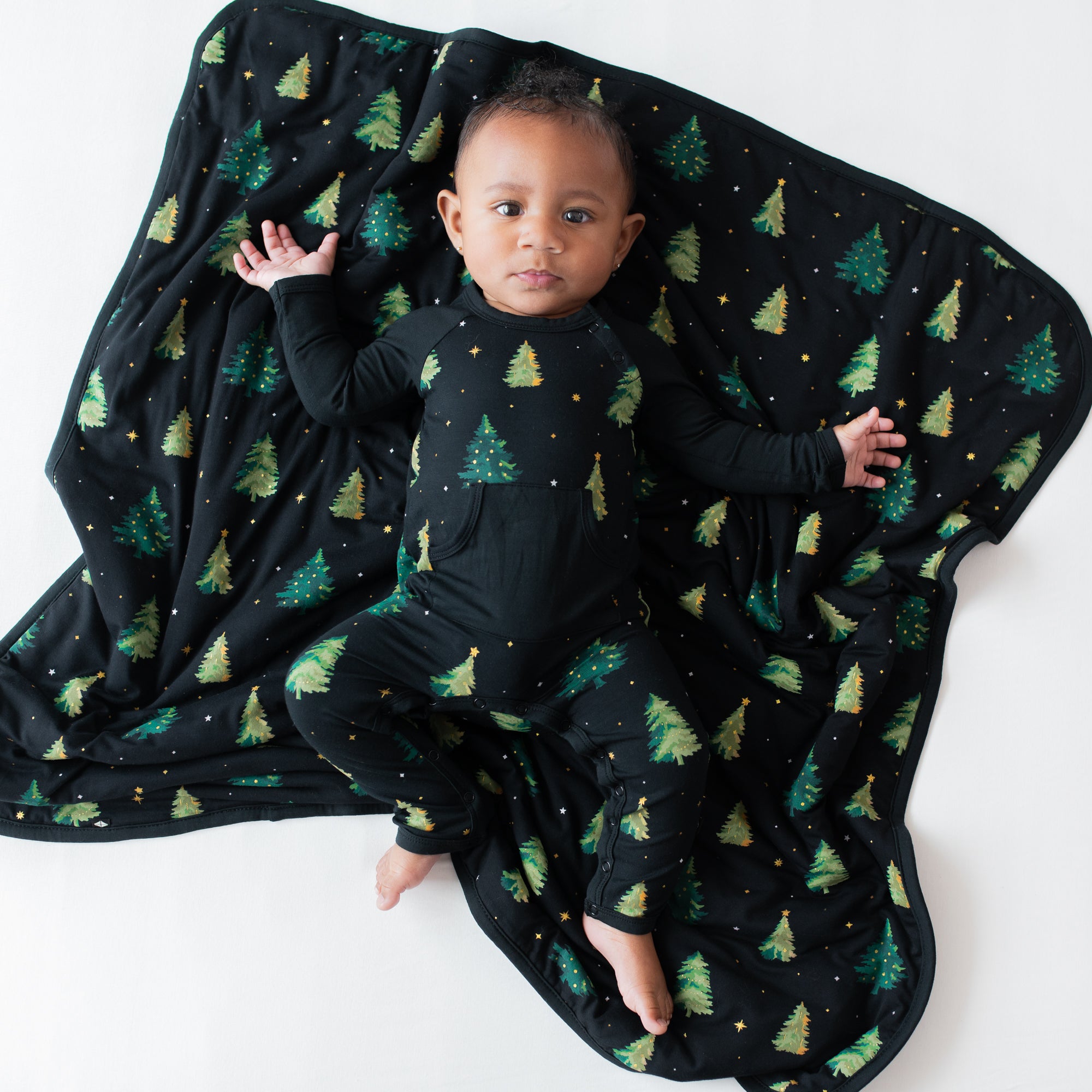 Infant laying down on a Baby Blanket in Twinkle Tree wearing the matching longall
