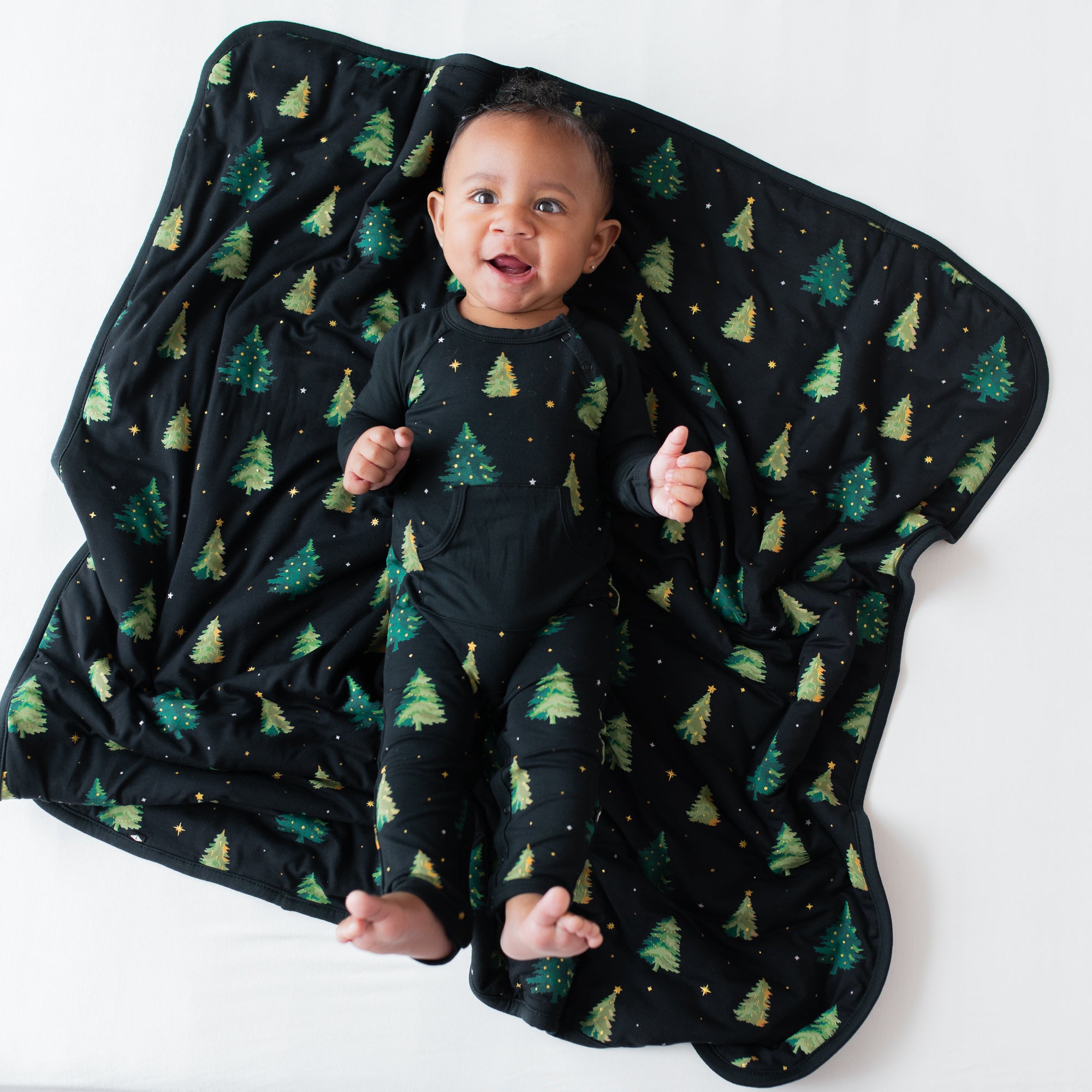 Infant wearing the Longall in Twinkle Tree laying on a matching baby blanket