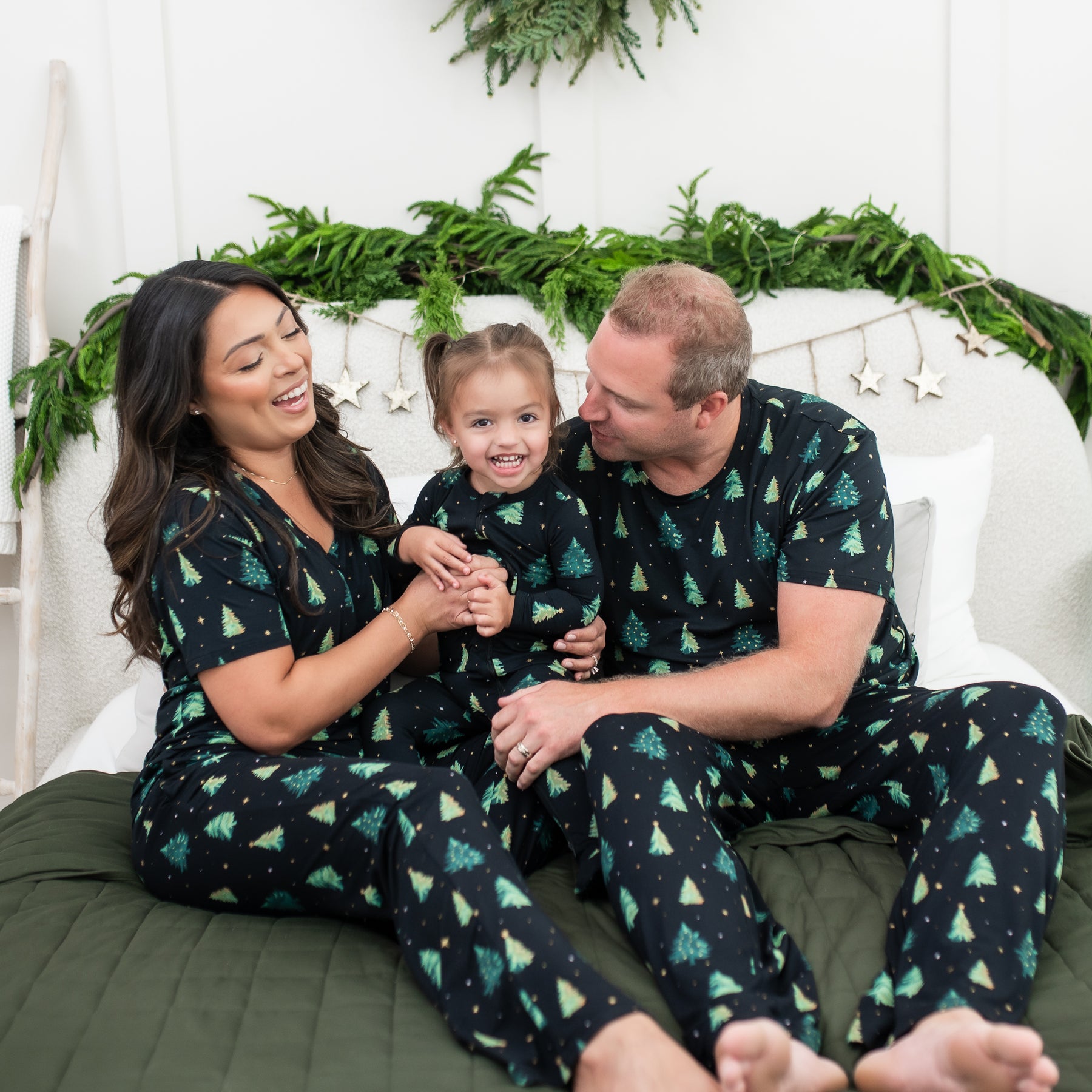 Family of three sitting on a bed matching in various items in Twinkle Tree