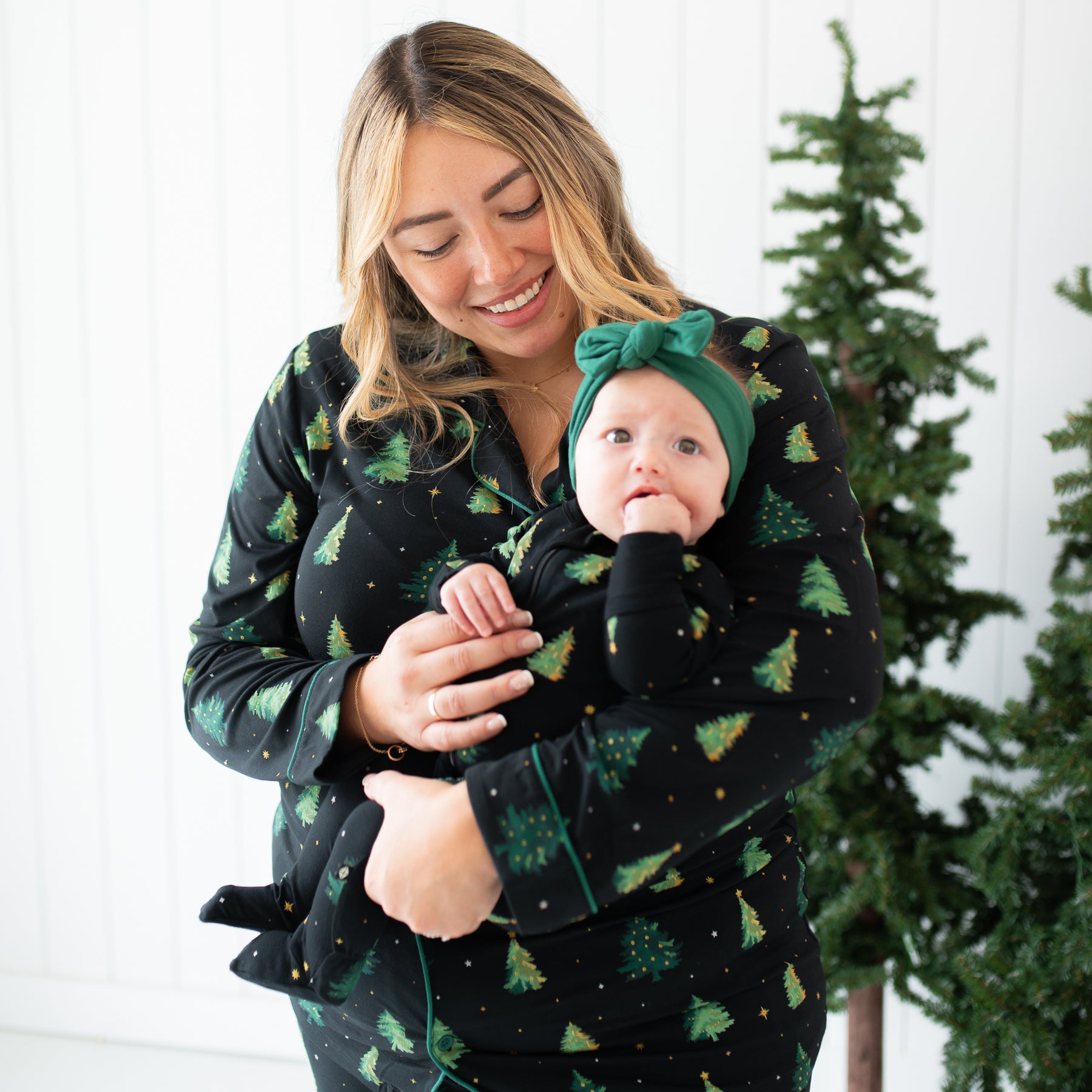 Mother wearing the Twinkle Tree long sleeve women's pajama set holding her daughter who is matching in the Zippered Footie in Twinkle Tree