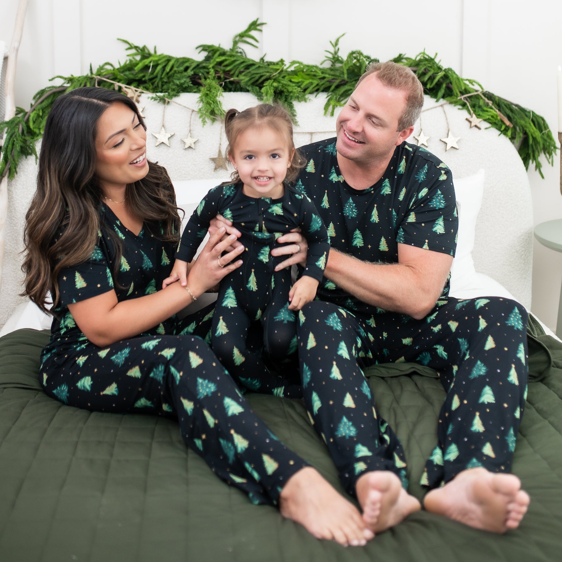 Family of three sitting on a bed matching in Twinkle Tree items