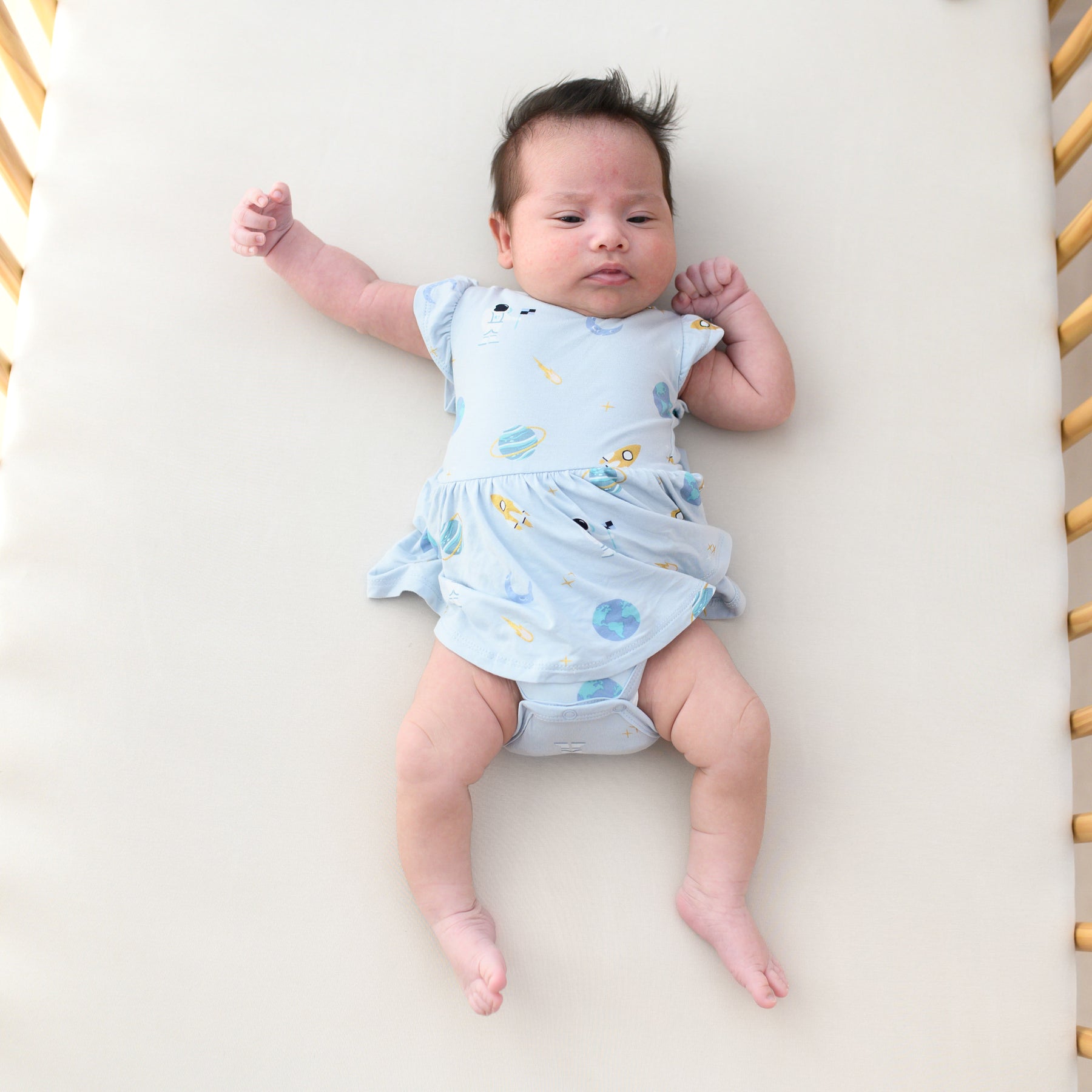 baby laying in crib wearing ice space twirl bodysuit dress