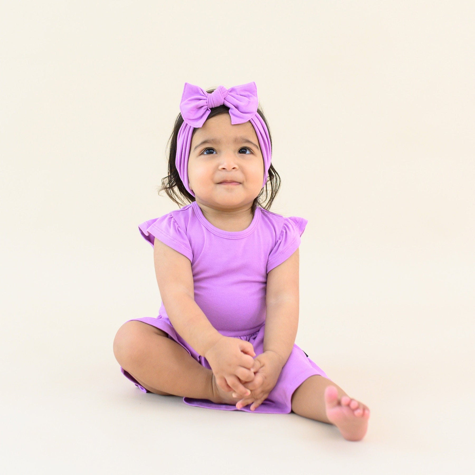 baby wearing twirl bodysuit dress and bow in poi