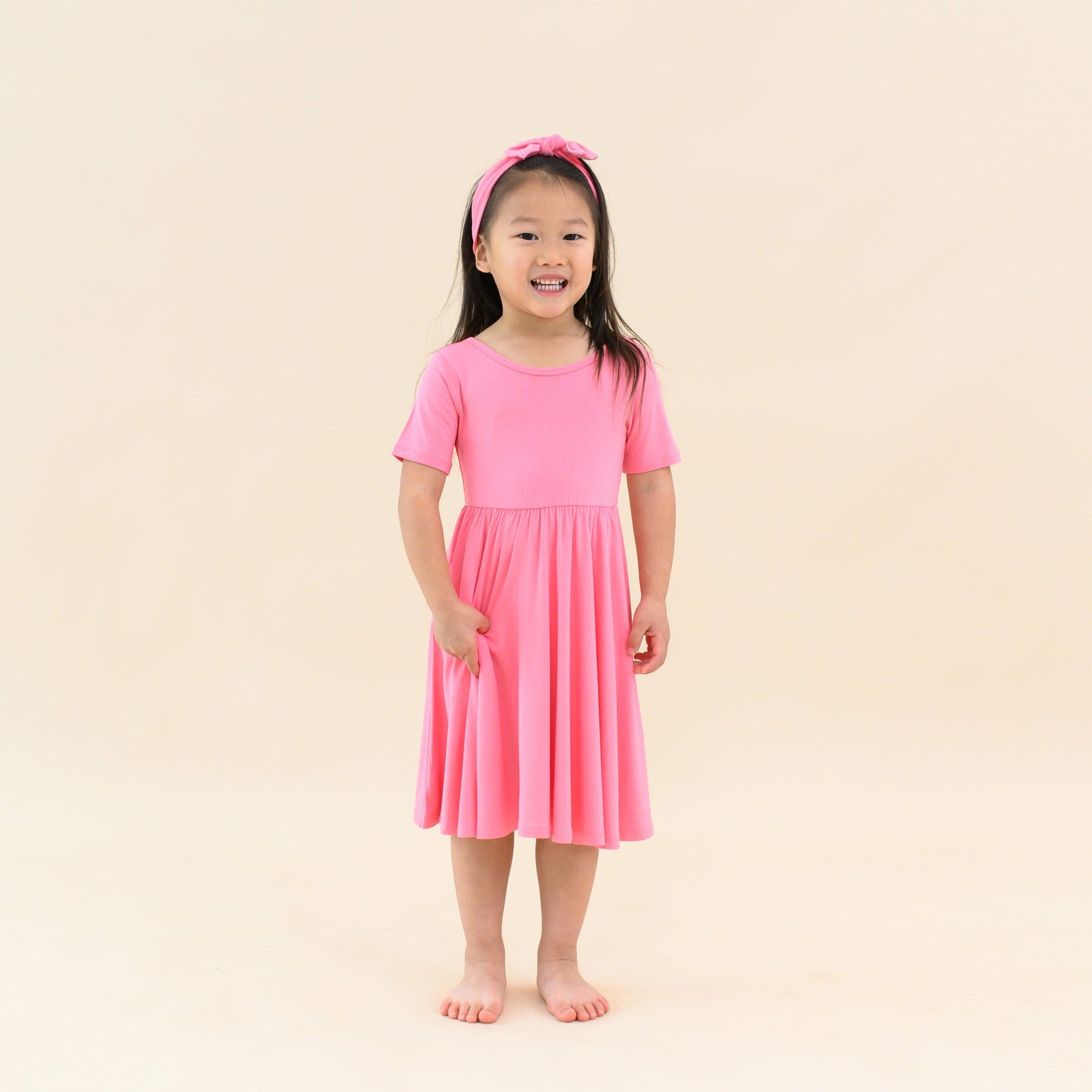 toddler modeling twirl dress in guava and matching bow