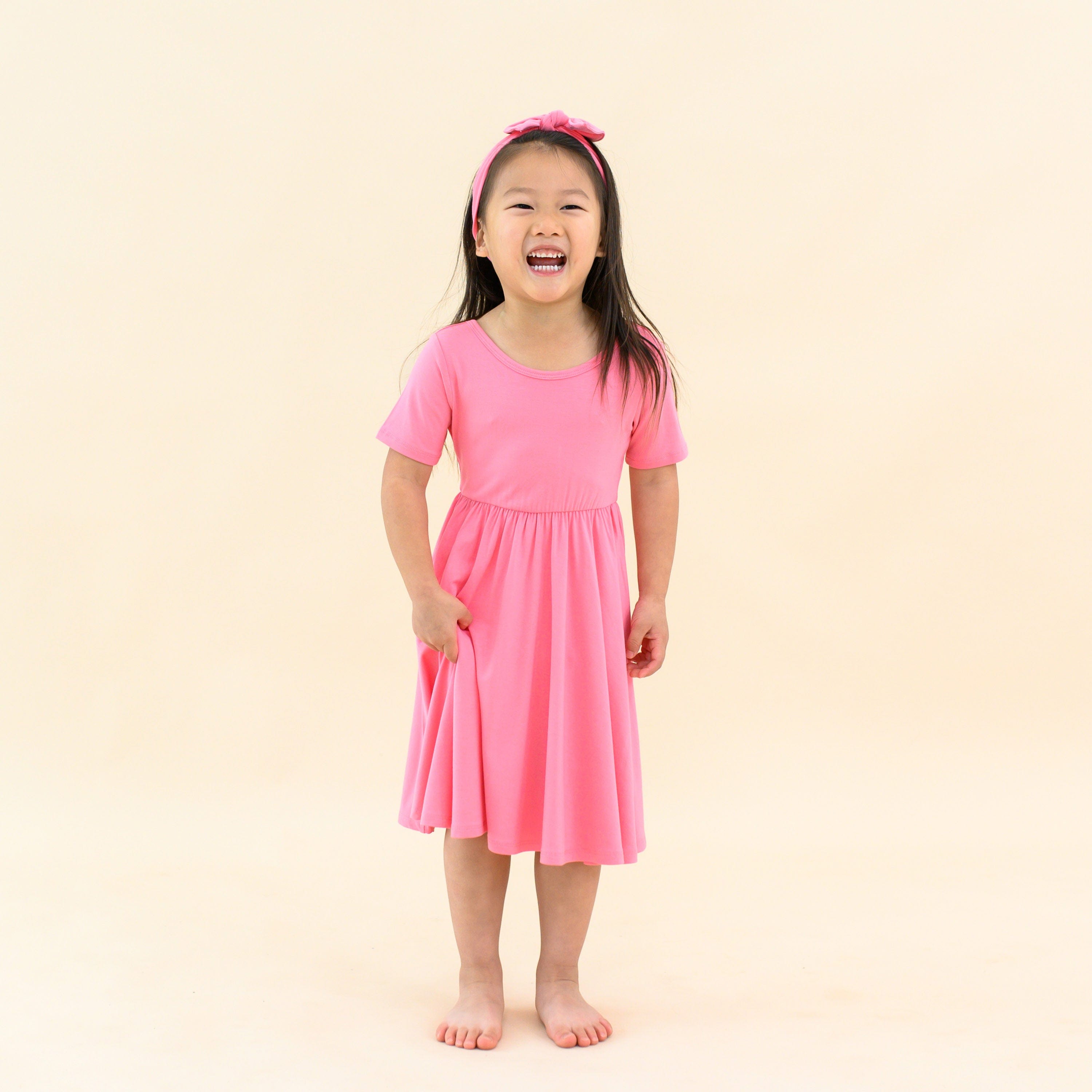 toddler modeling twirl dress in guava and matching bow