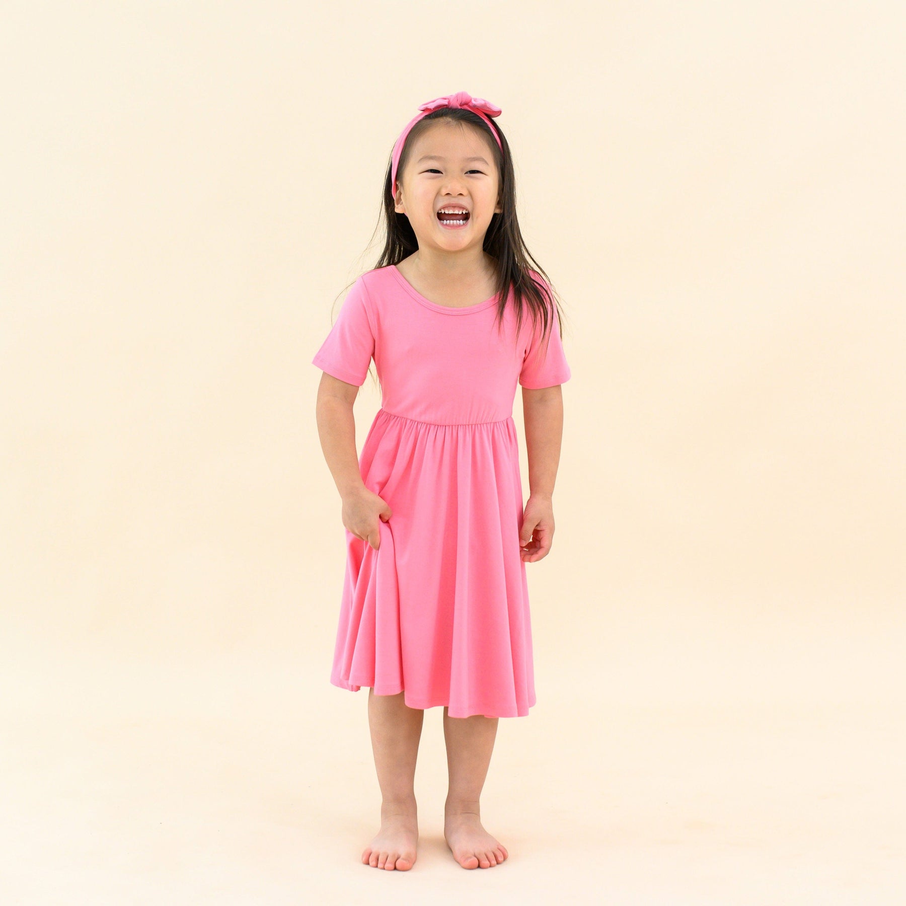 toddler modeling twirl dress in guava and matching bow