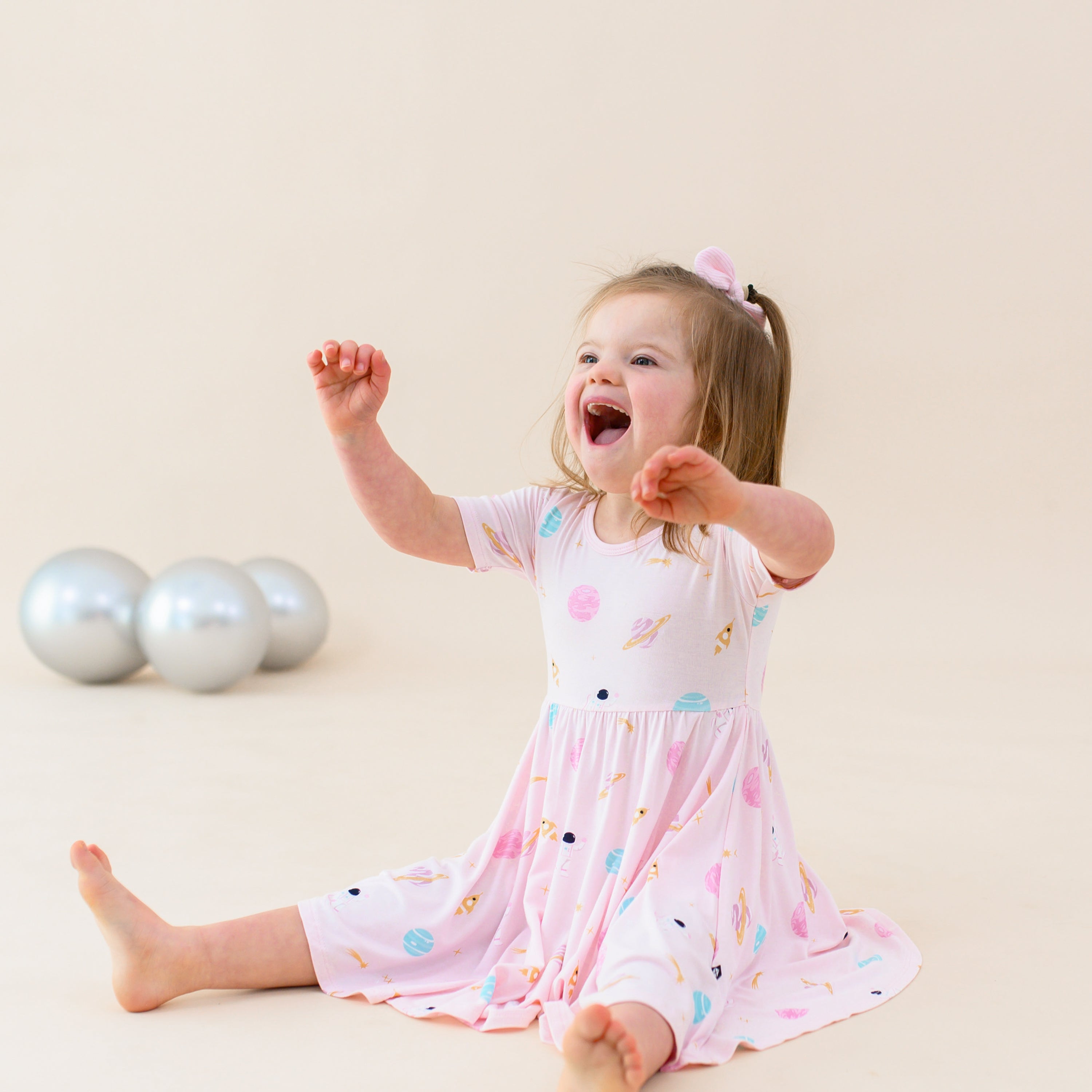 toddler smiling and sitting wearing sakura space twirl dress