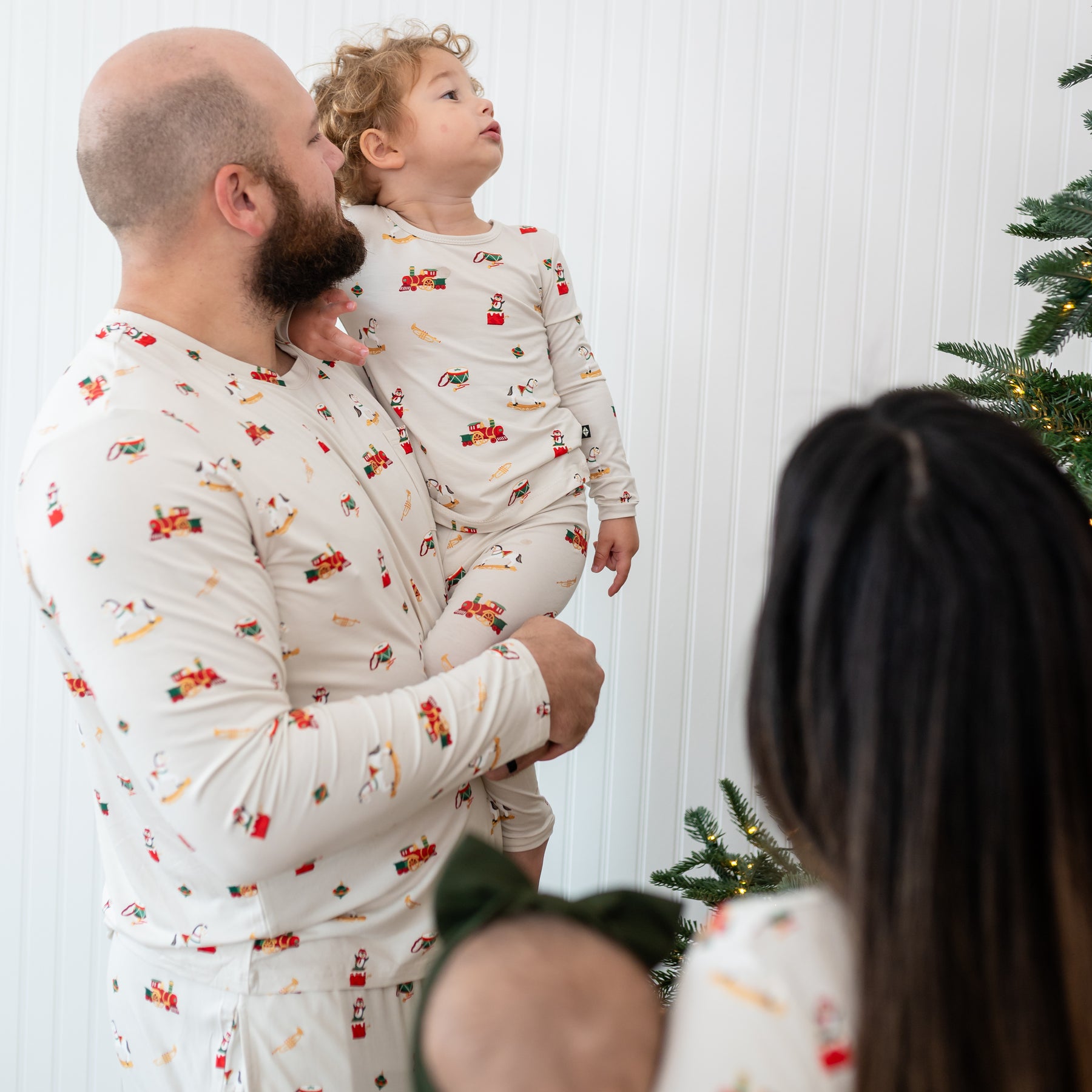 Father wearing the Men's Jogger Set in Vintage Toys holding his son both looking at the lit Christmas tree