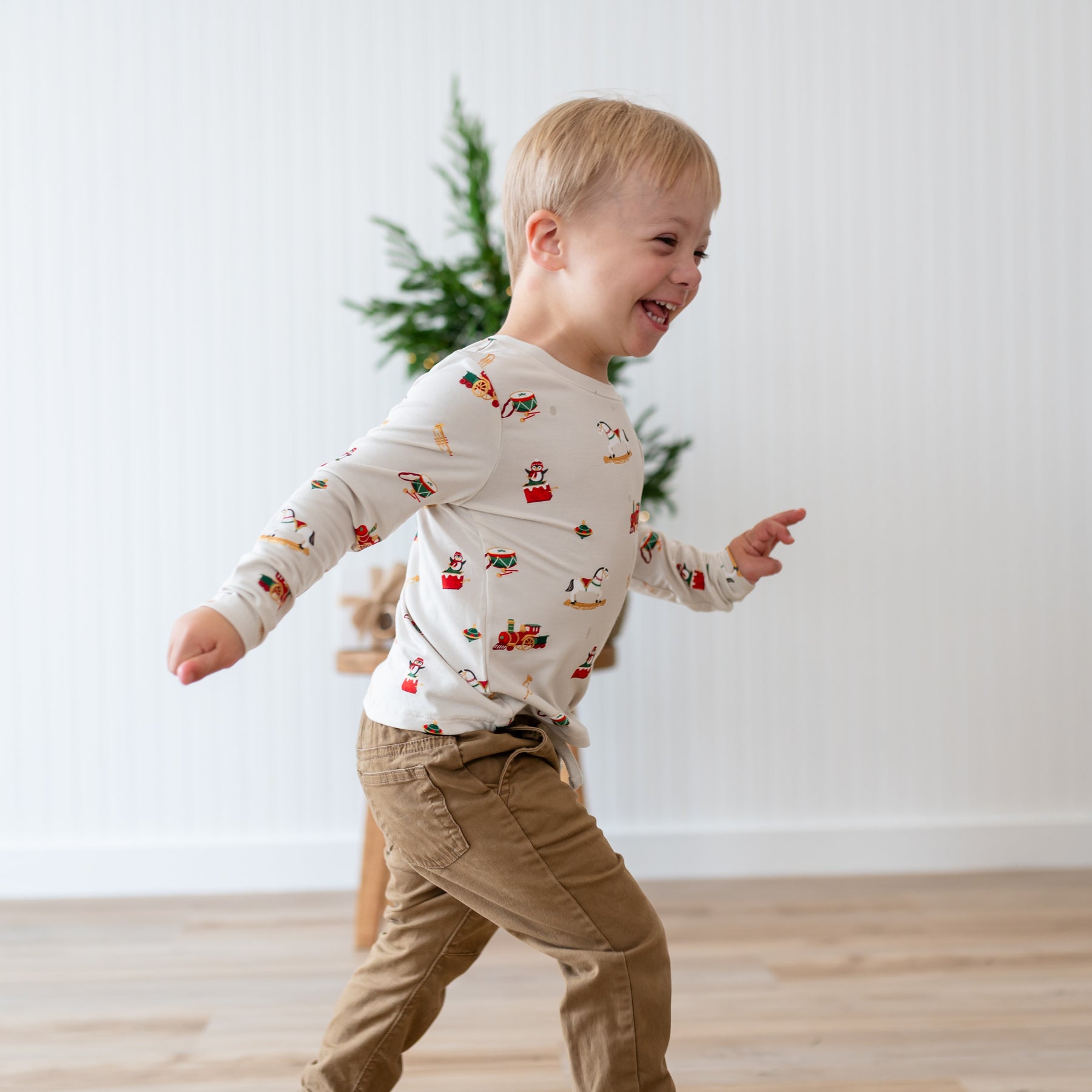Young smiling boy running wearing the Long Sleeve Toddler Crew Neck Tee in Vintage Toys