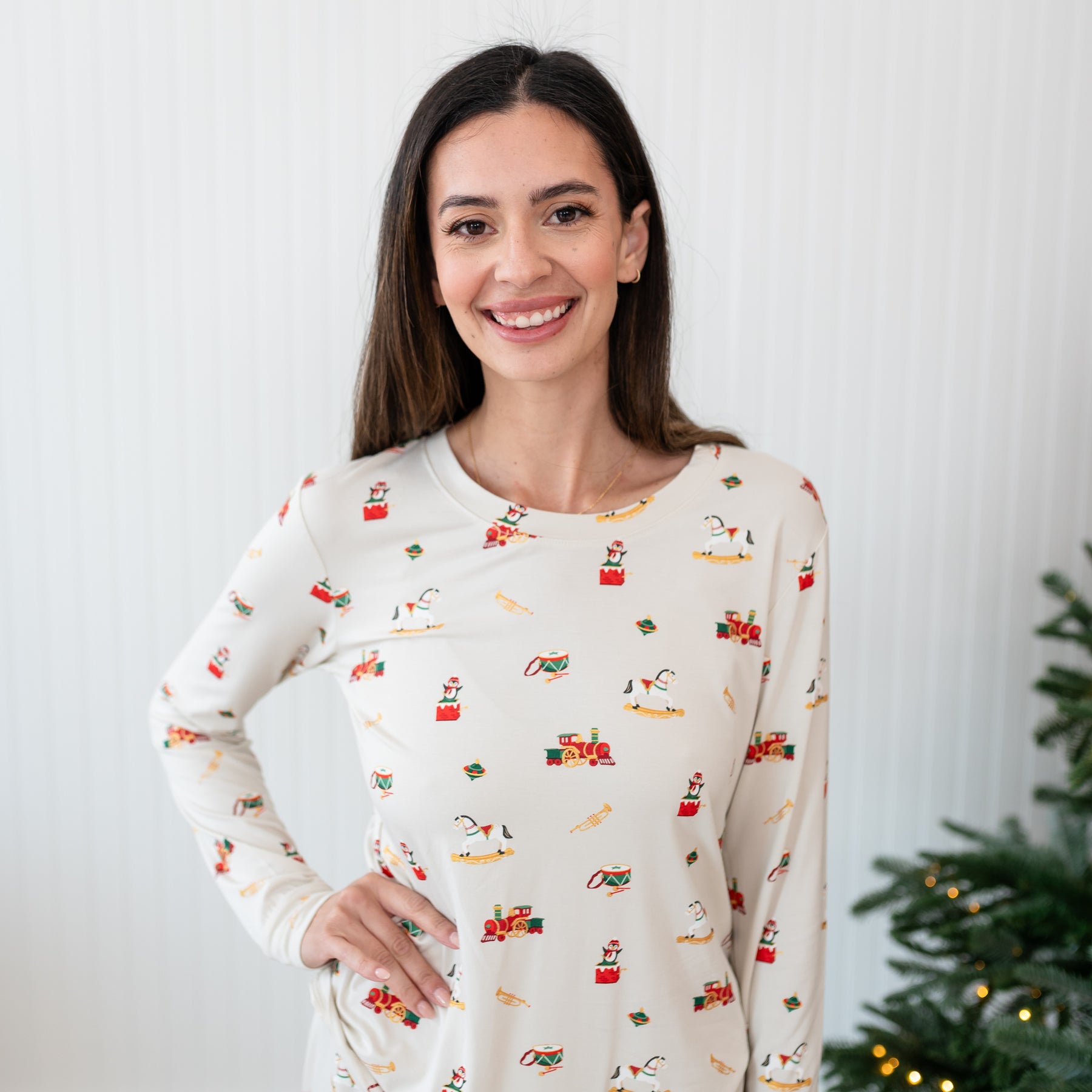 Close up of the top of the Women's Jogger Pajama Set in Vintage Toys shown on a smiling model with one hand on her hip standing in front of a white paneled wall