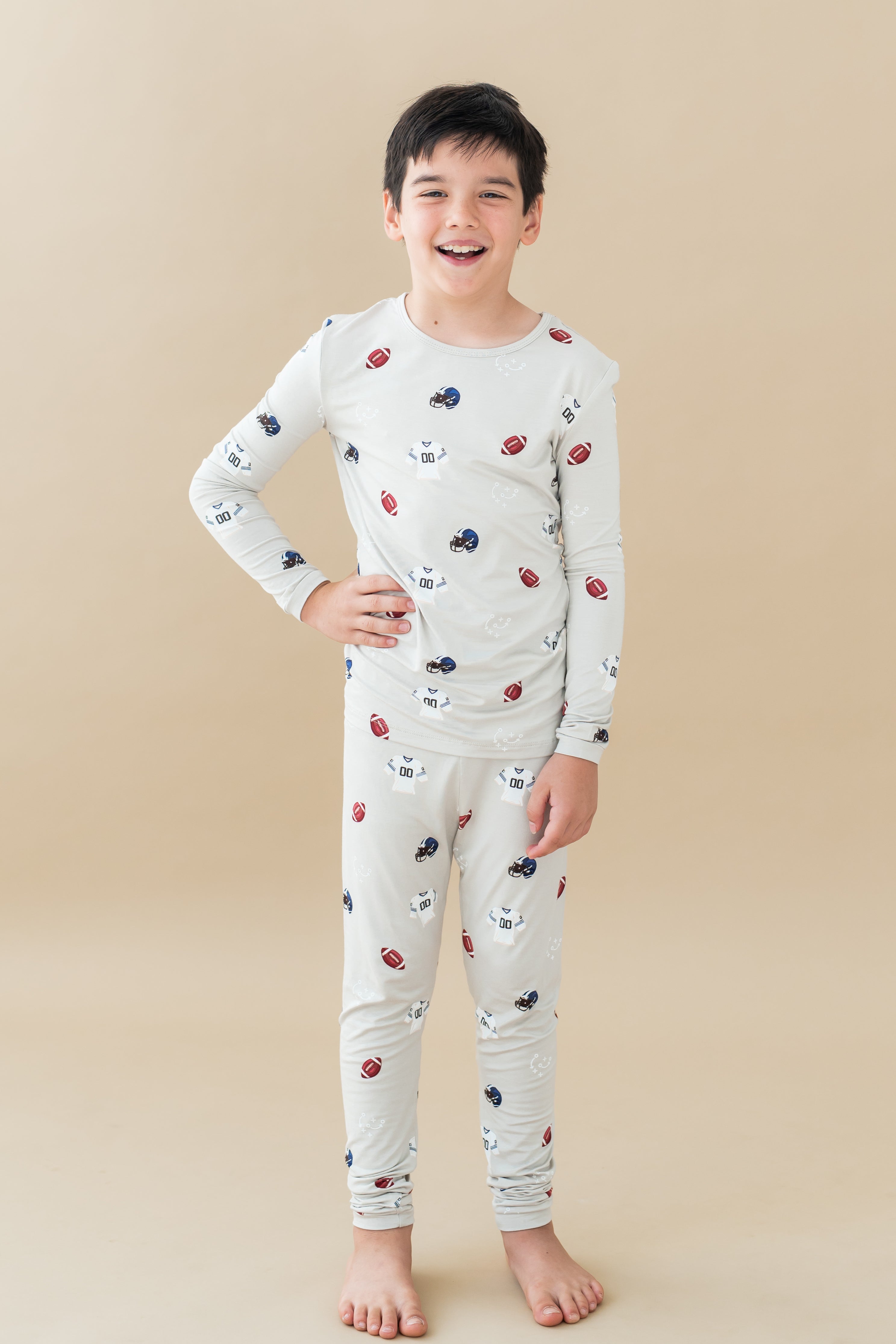 Boy wearing Long Sleeve Pajamas in Vintage Football print on a beige background