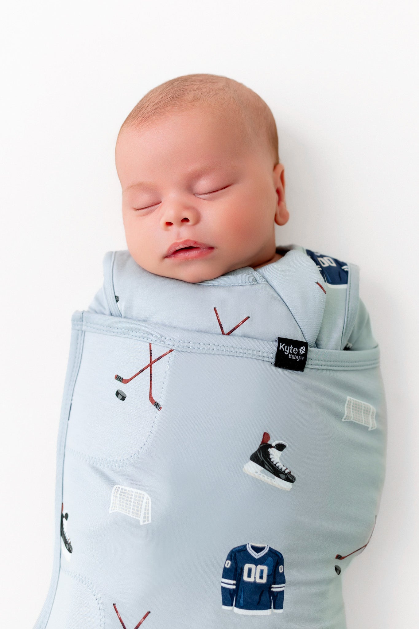 Close up of Baby sleeping in Sleep Bag Swaddler with Vintage Hockey 1.0 print on a white background
