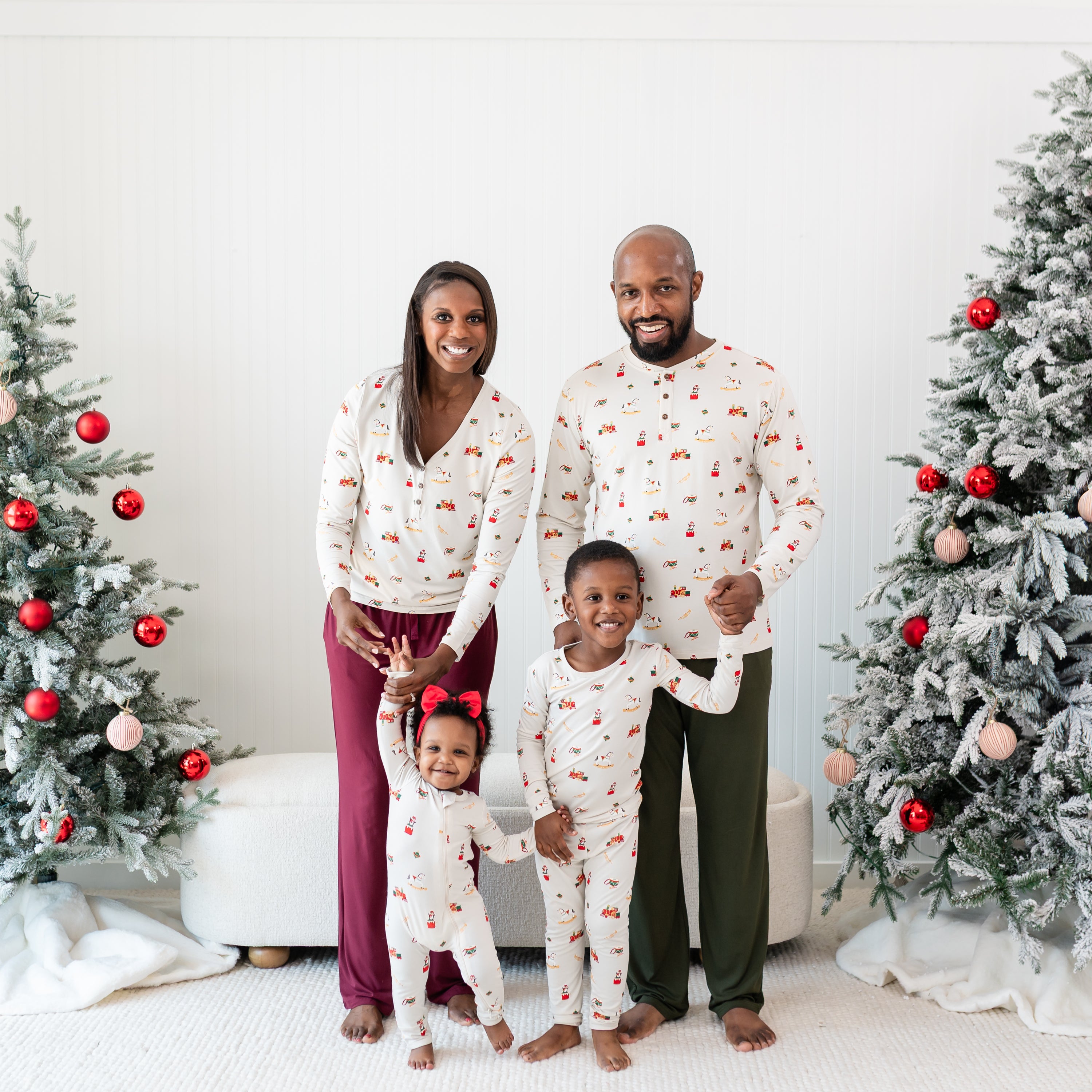 Family of four standing between two decorated Christmas trees wearing various items in Vintage Toys