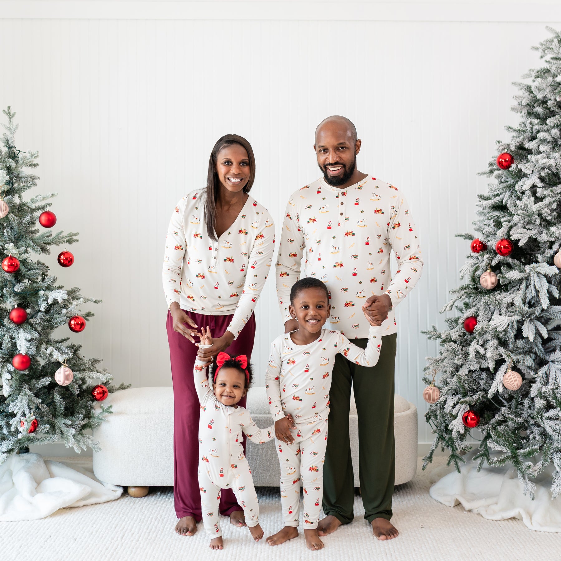Family of four standing between two decorated Christmas trees wearing various items in Vintage Toys