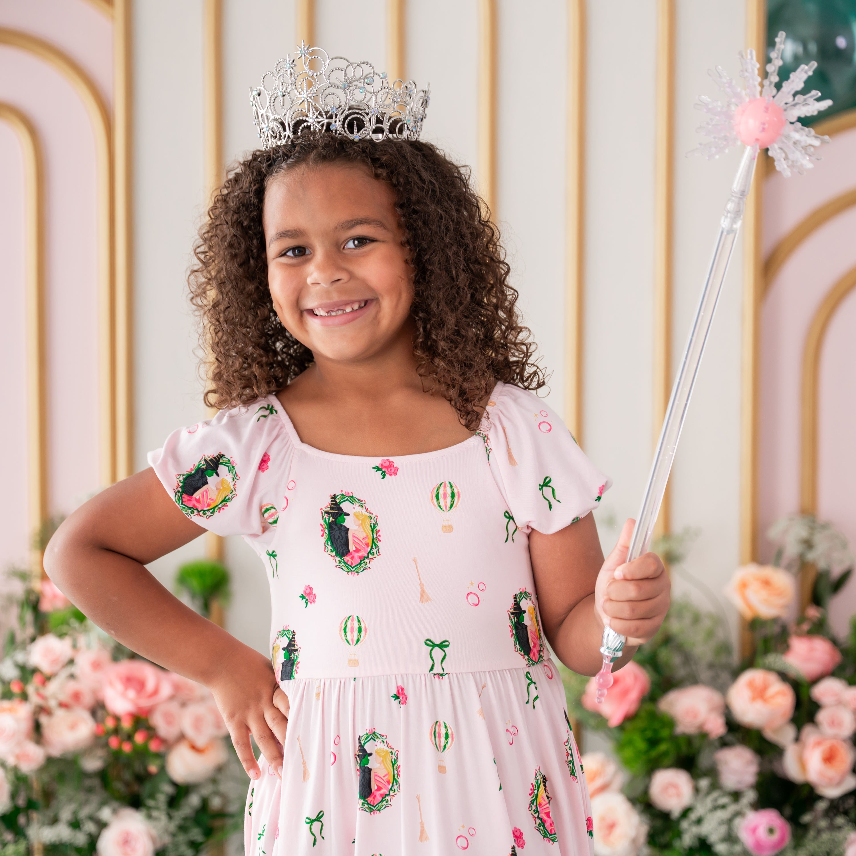 Smiling girl wearing the Puff Sleeve Twirl Dress in Wicked paired with a play tiara and wand