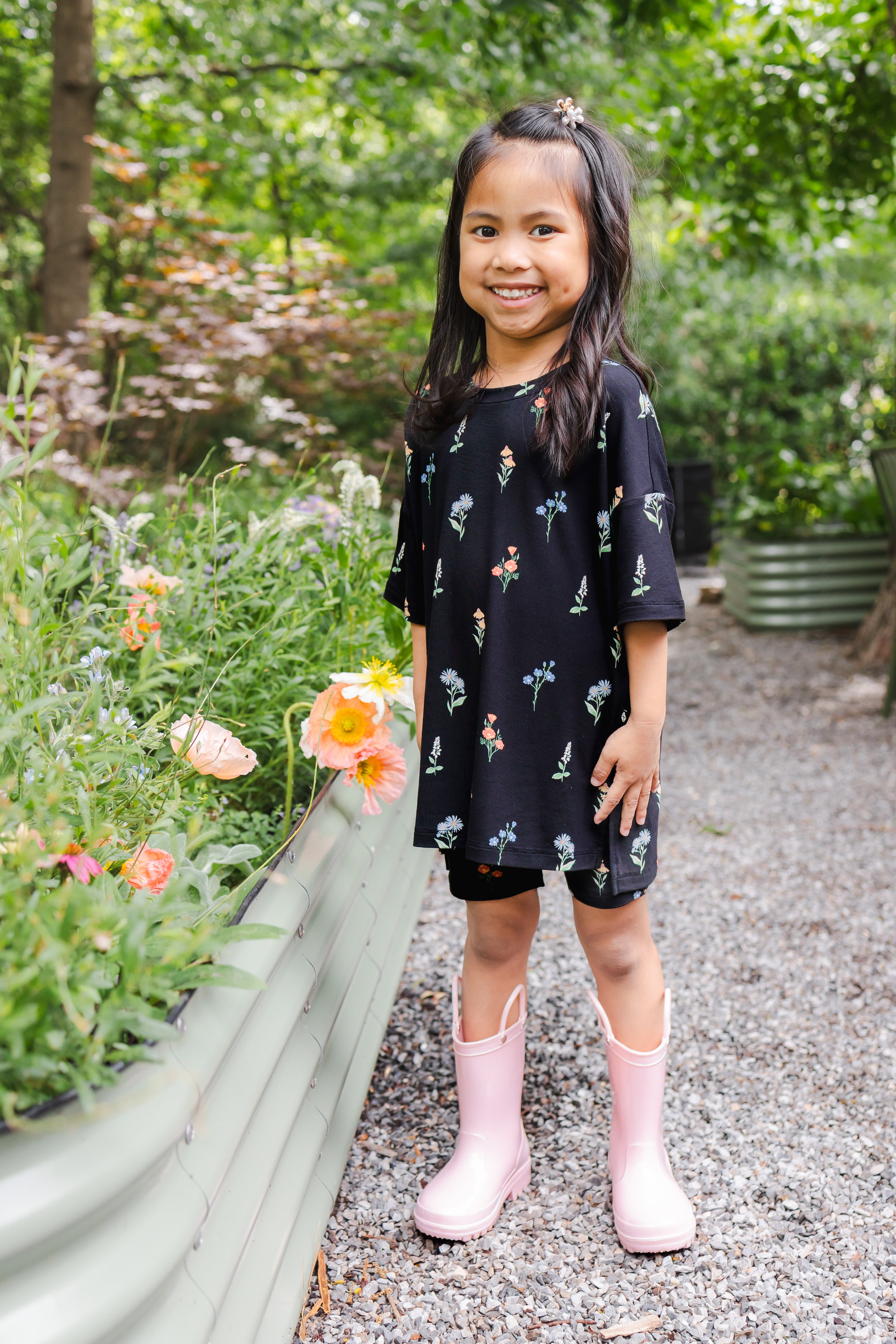 Girl standing outdoors wearing Toddler Biker Short Set in Midnight Wildflower print and pink boots